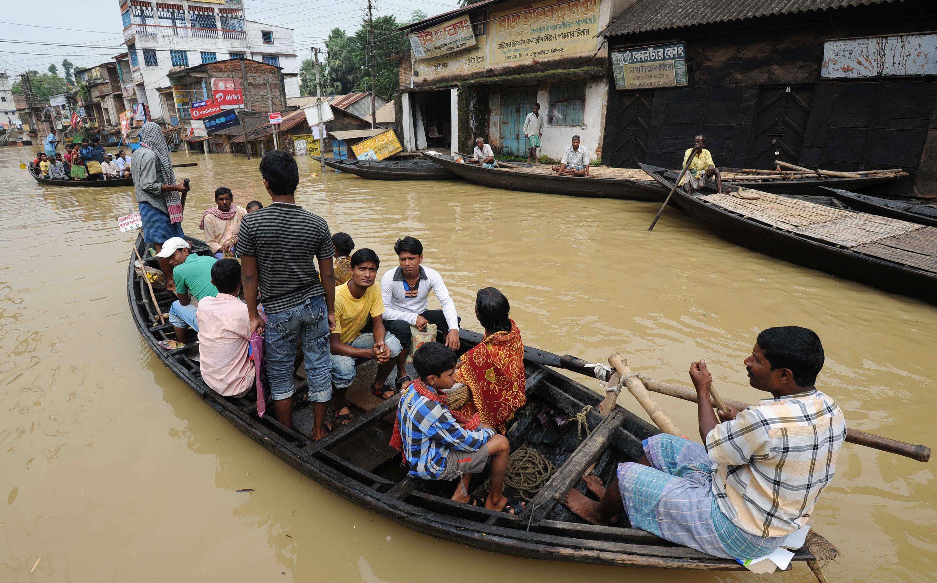 Indian people sit on a boat on a flooded road in Ghatal, some 95 kilometers south of Kolkata, on August 4, 2015.