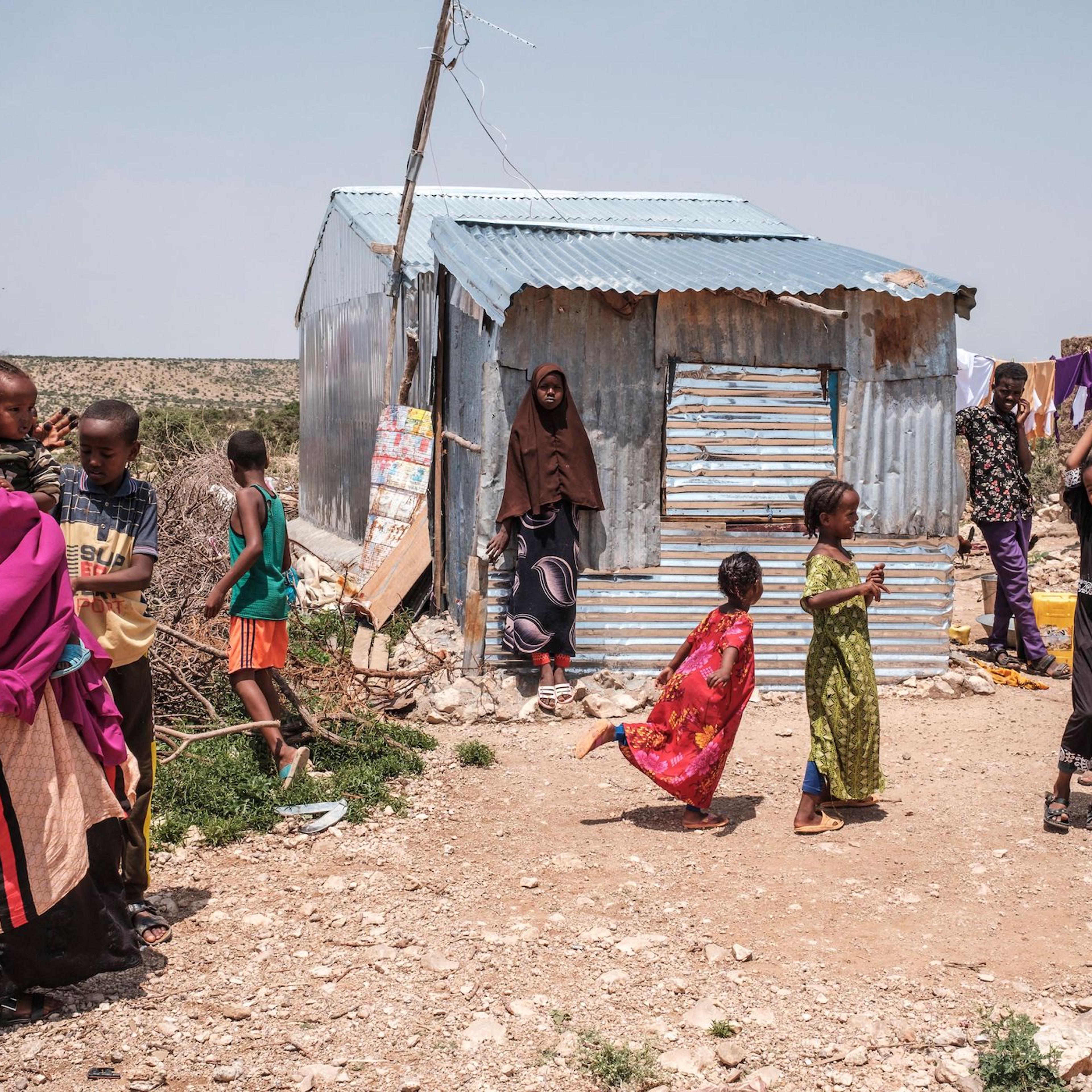People stand outside of their homes in an informal settlement of internally displaced people in the outskirts of the city of Hargeisa, Somaliland, on September 16, 2021.