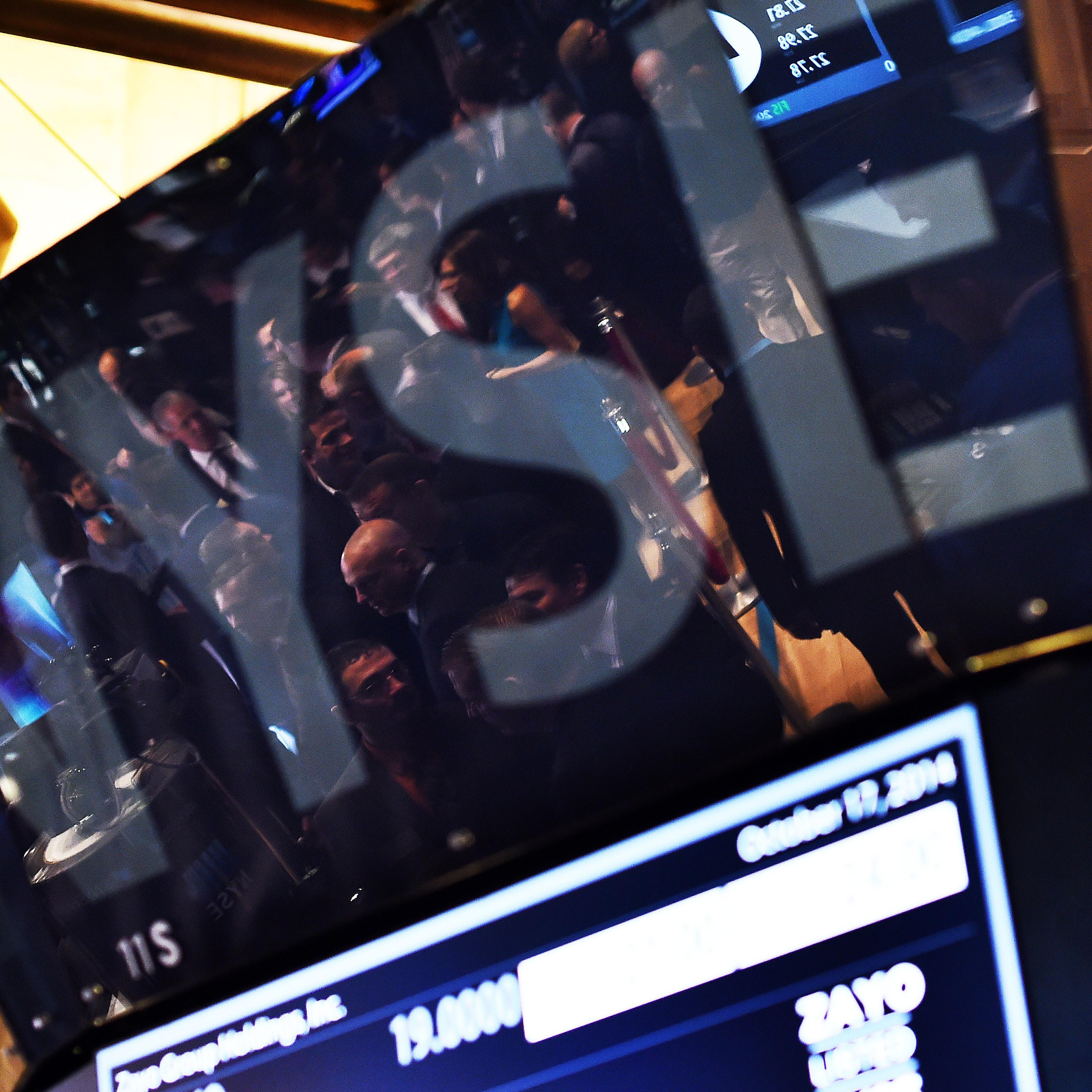 Traders are seen reflected on an electronic display as they work on the floor of the New York Stock Exchange on October 17, 2014 in New York.