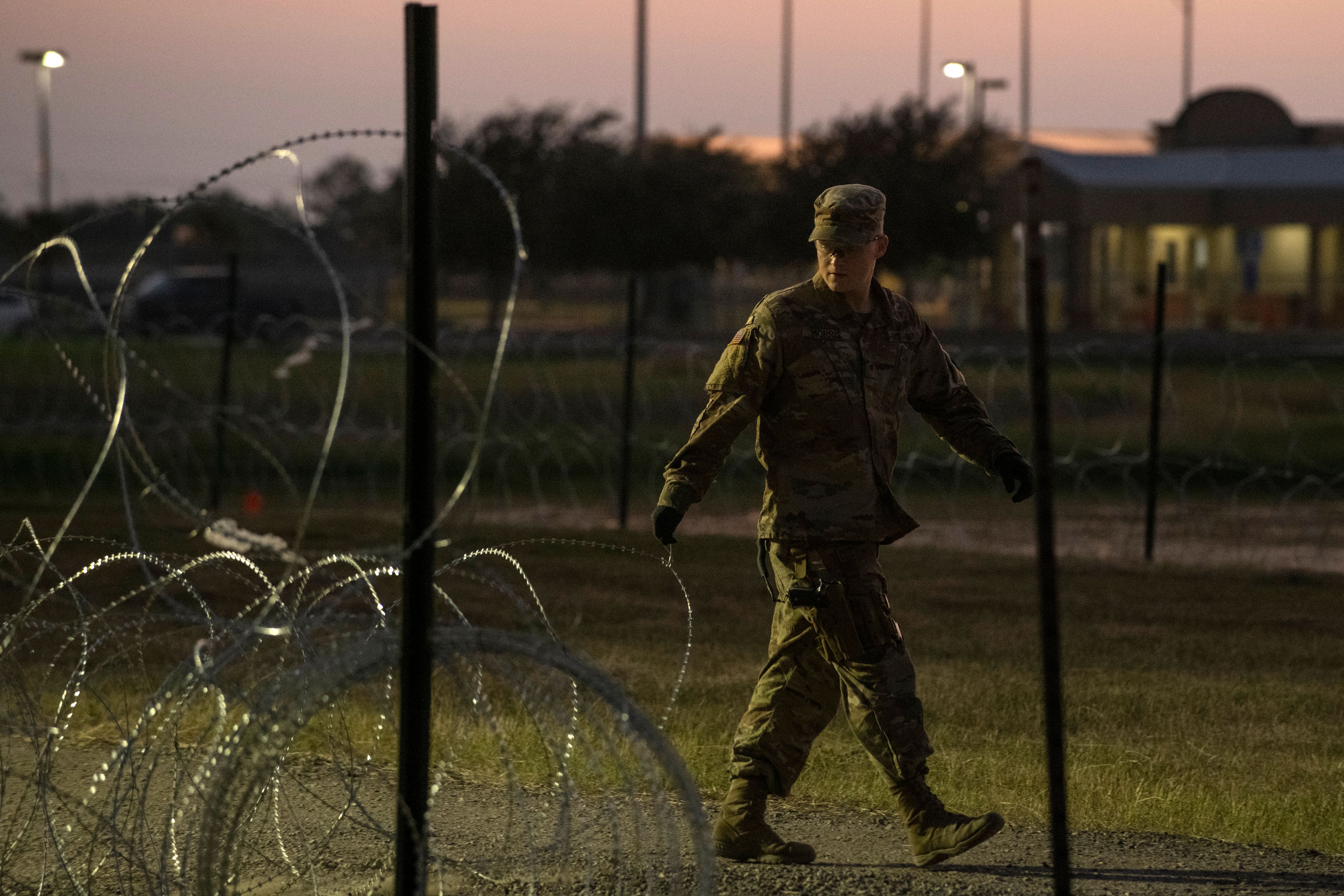 A US Army soldier closes a razor-wire gate at a compound where the military is erecting an encampment near the US-Mexico border crossing at Donna, Texas, on November 6, 2018.