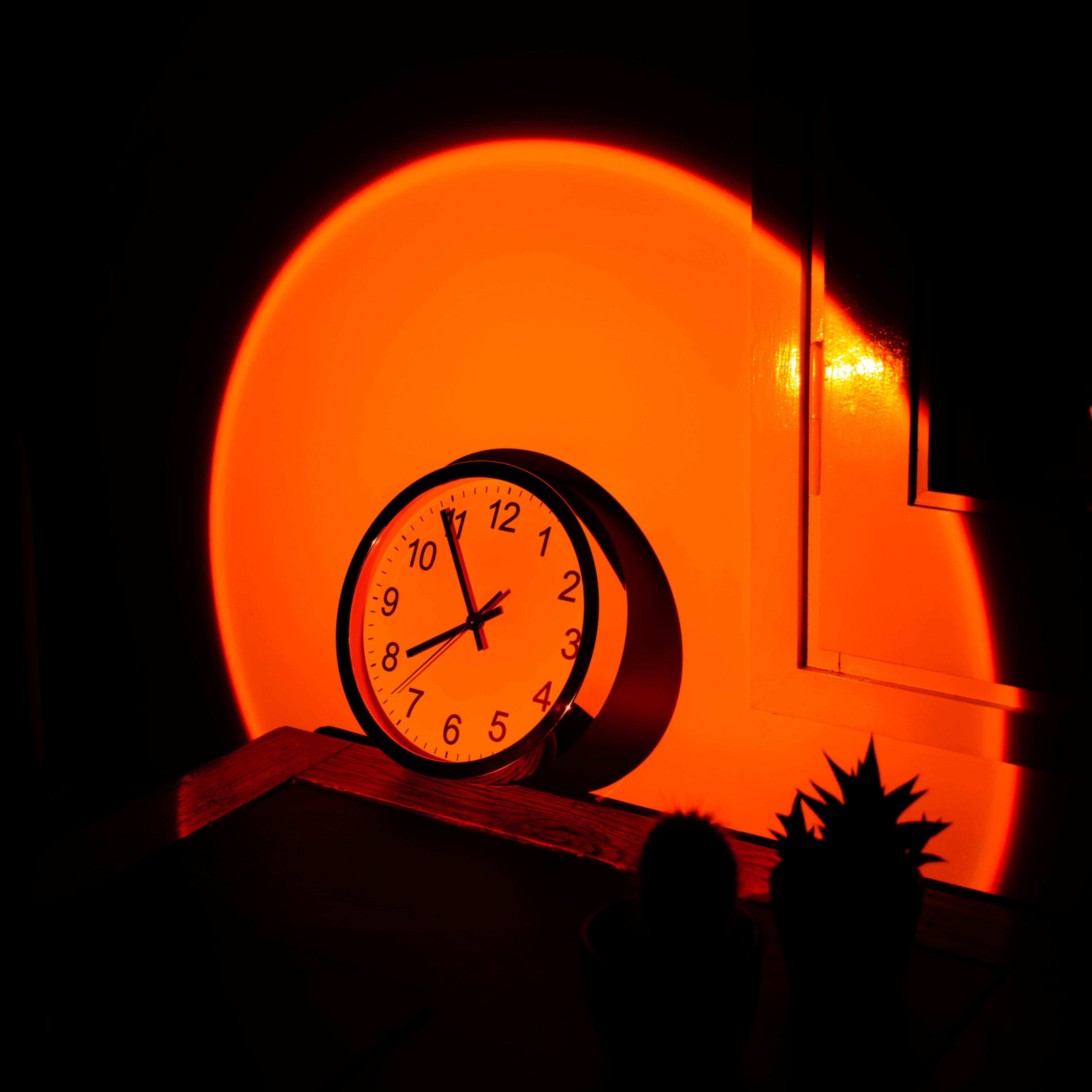 Wall clock in office desk with big sunset sun light effect.