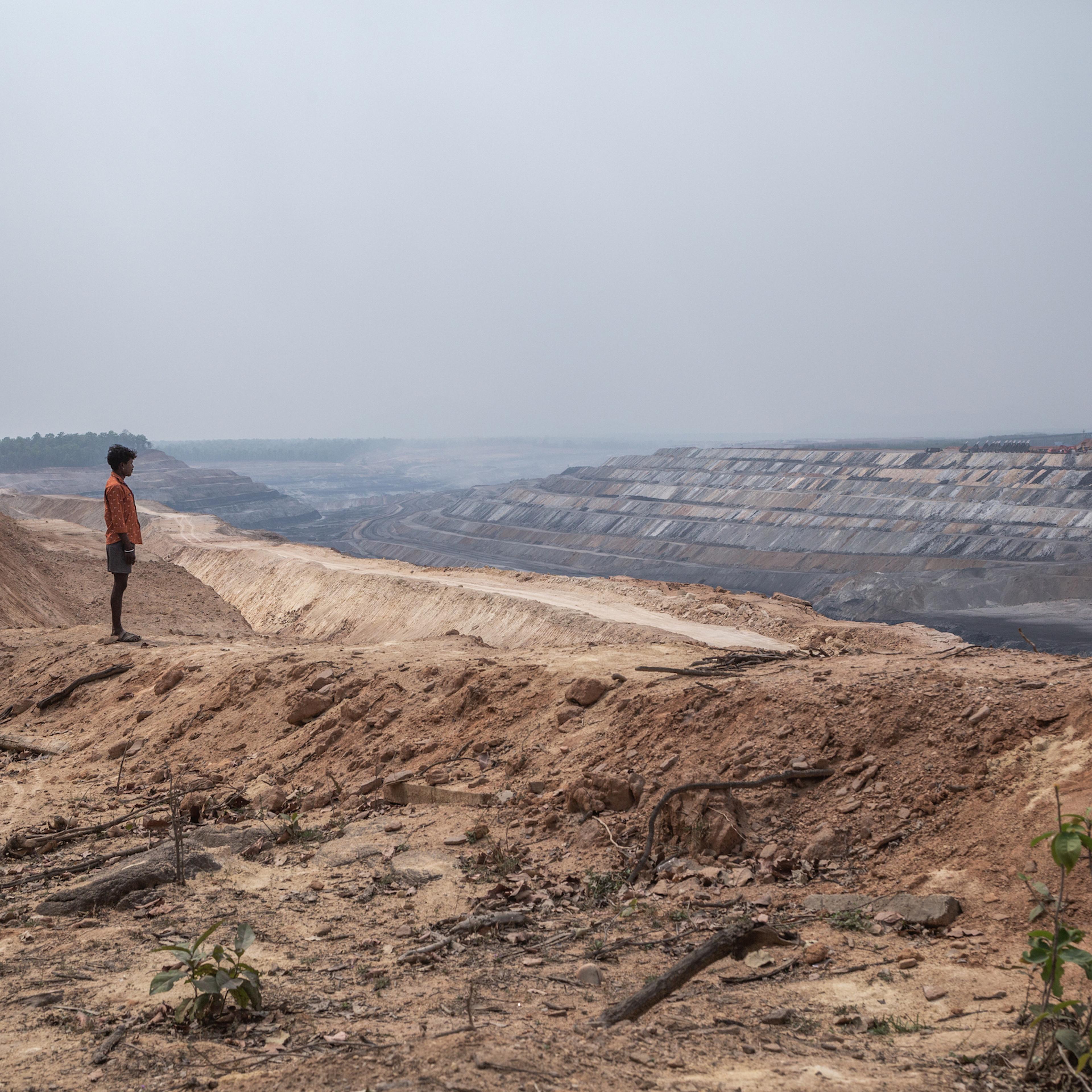 A tribal villager is standing in front of PEKB coal mine in Chhattisgarh district.