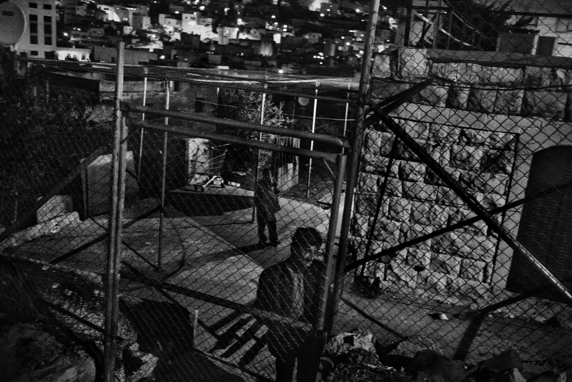 Imad Abu Shamsiyeh closes the metal fence that he placed around and above his house in the Tel Rumeida neighborhood to protect him and his family from more settler attacks, Hebron, November 2015.