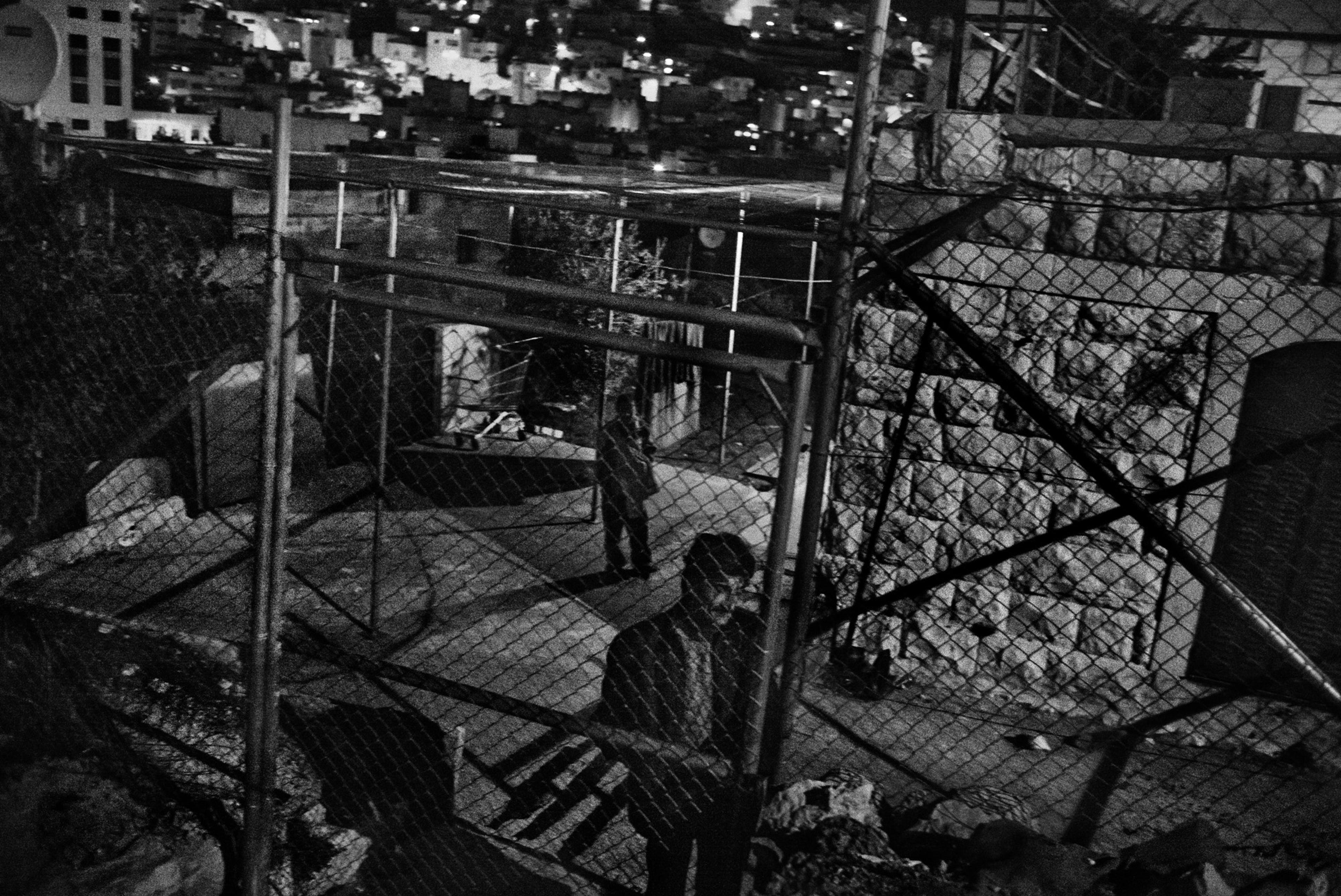 Imad Abu Shamsiyeh closes the metal fence that he placed around and above his house in the Tel Rumeida neighborhood to protect him and his family from more settler attacks, Hebron, November 2015.