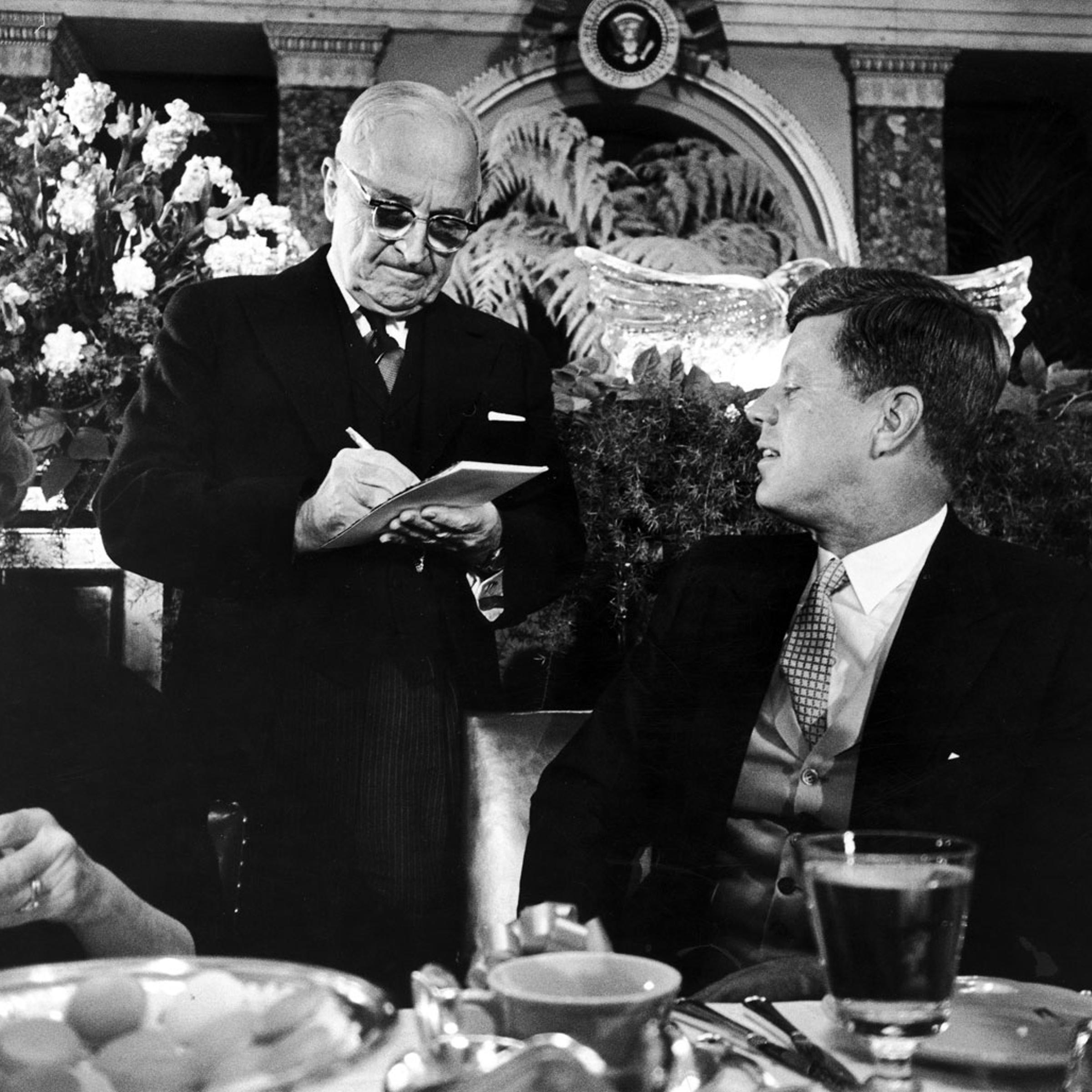 President John Kennedy watches former President Harry Truman sign an autograph for him at the inaugural luncheon, 1961.
