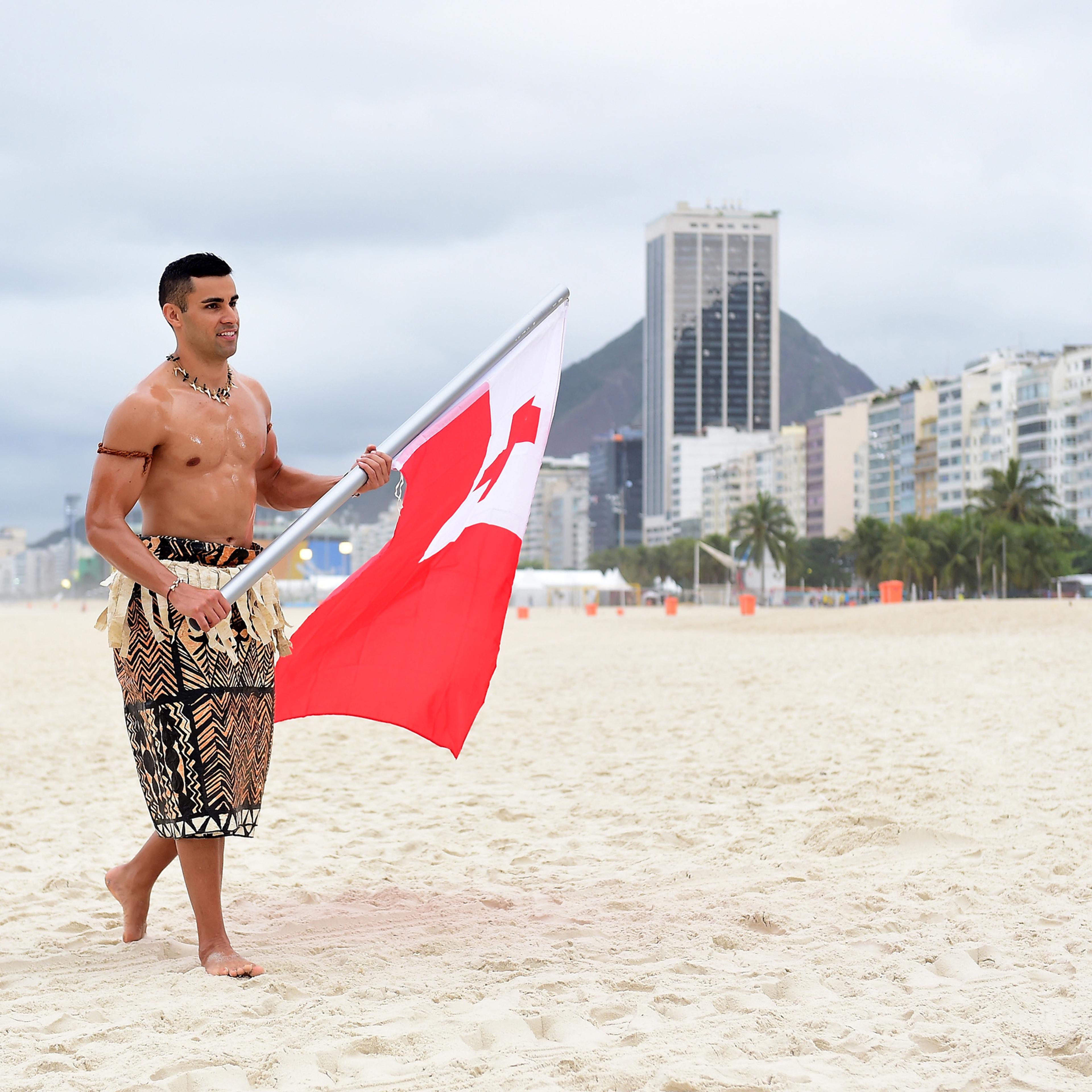 RIO DE JANEIRO, BRAZIL - AUGUST 08: Pita Taufatofua of Tonga walks along the sand with his country's flag to the NBC Today show set at Copacabana Beach on August 8, 2016 in Rio de Janeiro, Brazil. (Photo by Harry How/Getty Images)