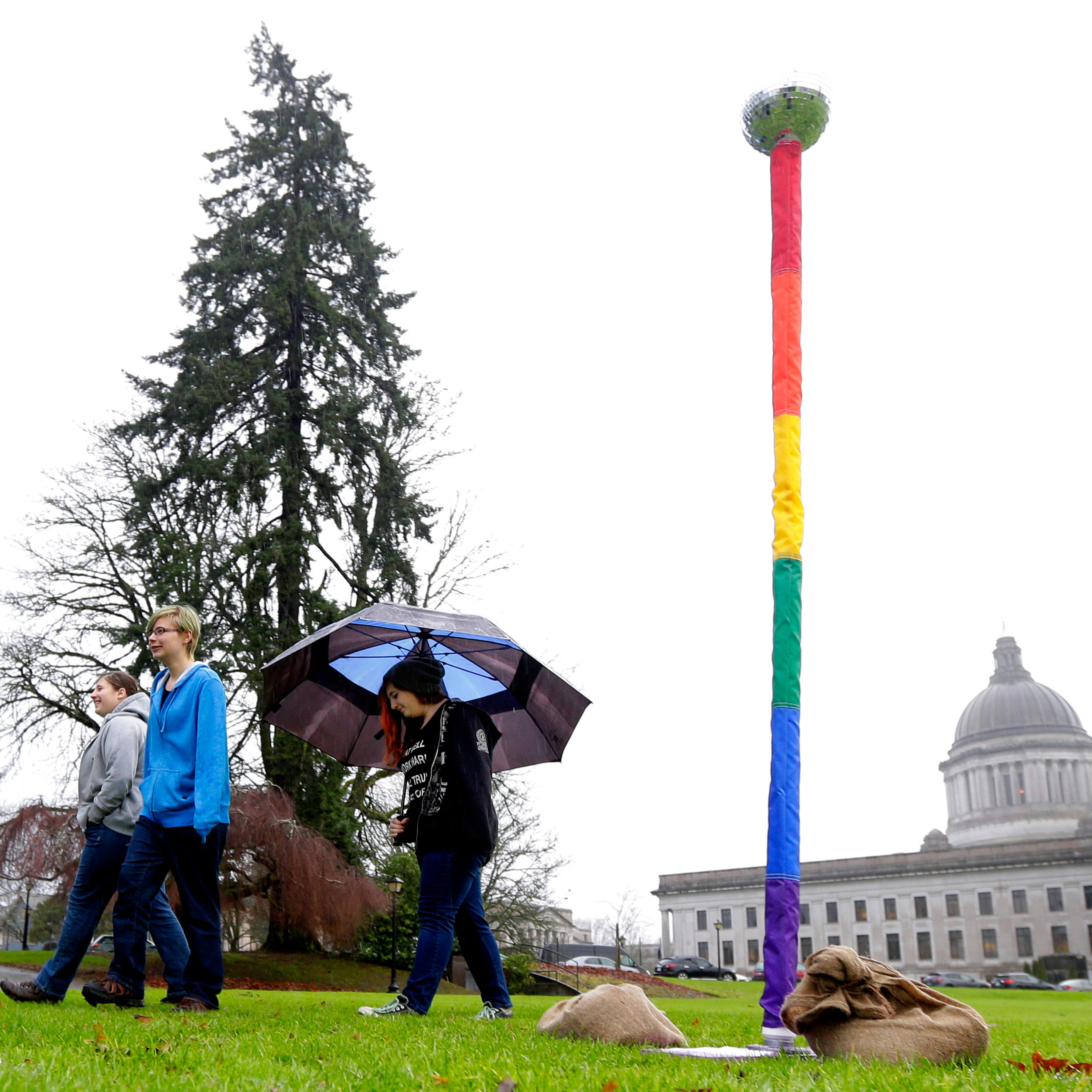 From left, siblings Kelli, Caitlynn, and Kerri Ray walk near a "Festivus Pole" supporting gay rights that they helped their father, Robert Ray, put up on Dec. 21, 2015, at the Capitol in Olympia, Wash.