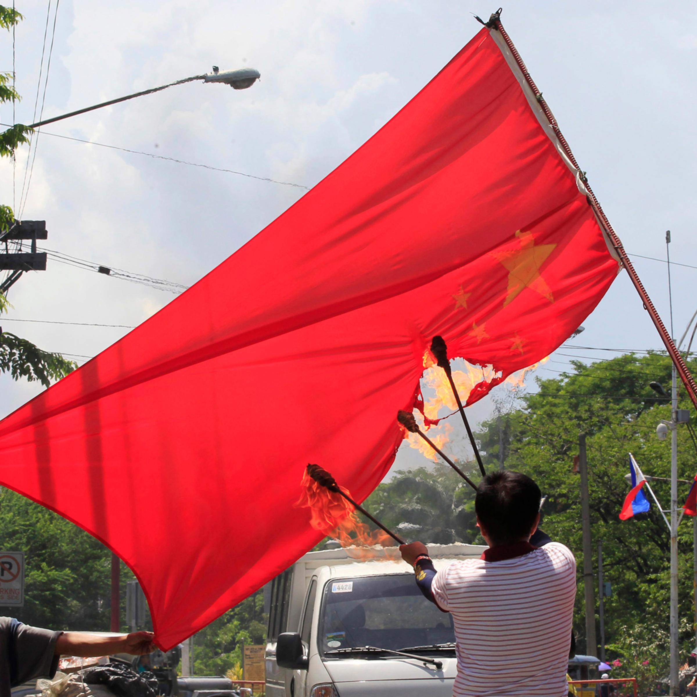 Abner Afuang, a retired policeman, sets fire to an inverted Chinese national flag in a protest action in Manila,