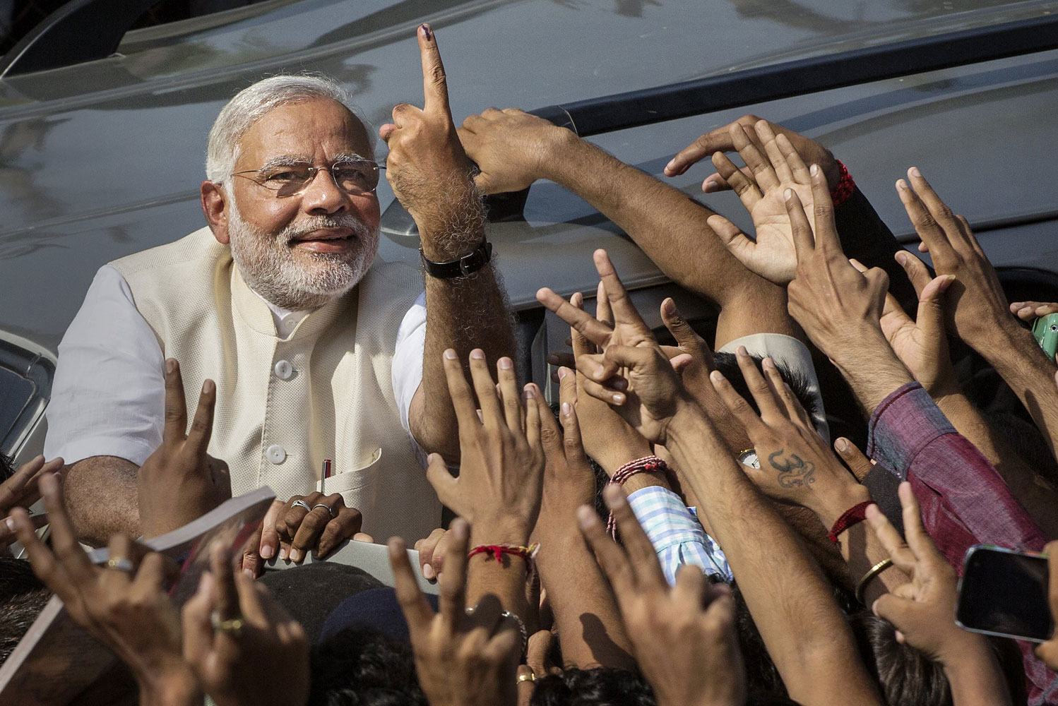 BJP leader Narendra Modi shows his inked finger to supporters as he leaves a polling station after voting on April 30, 2014 in Ahmedabad, India.