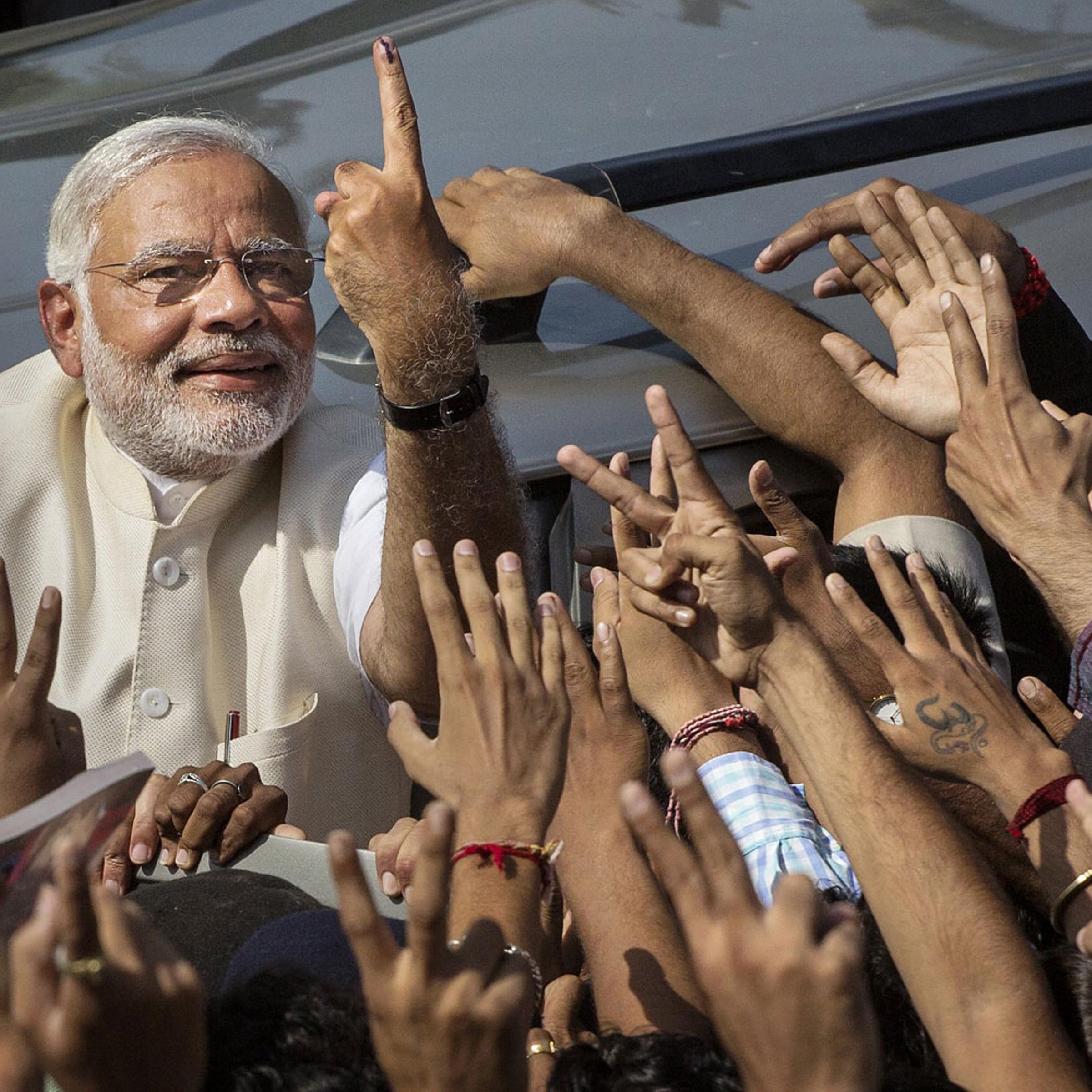 BJP leader Narendra Modi shows his inked finger to supporters as he leaves a polling station after voting on April 30, 2014 in Ahmedabad, India.