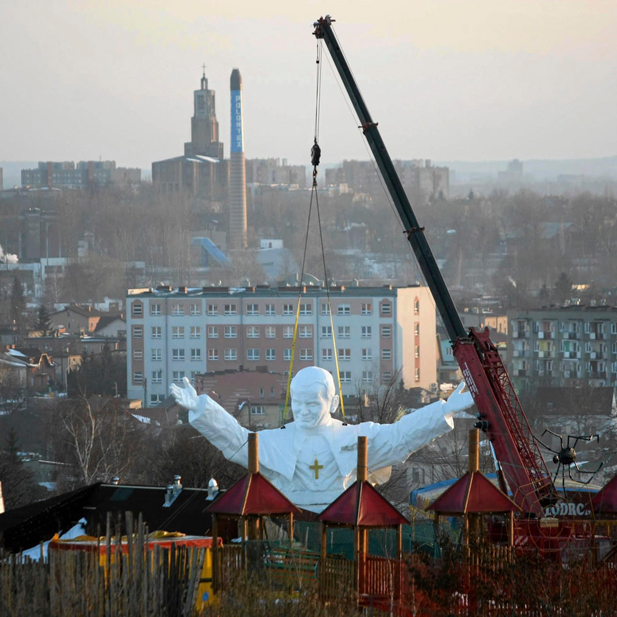 Monument to late Pope John Paul II is winched into position behind an amusement park in Czestochowa