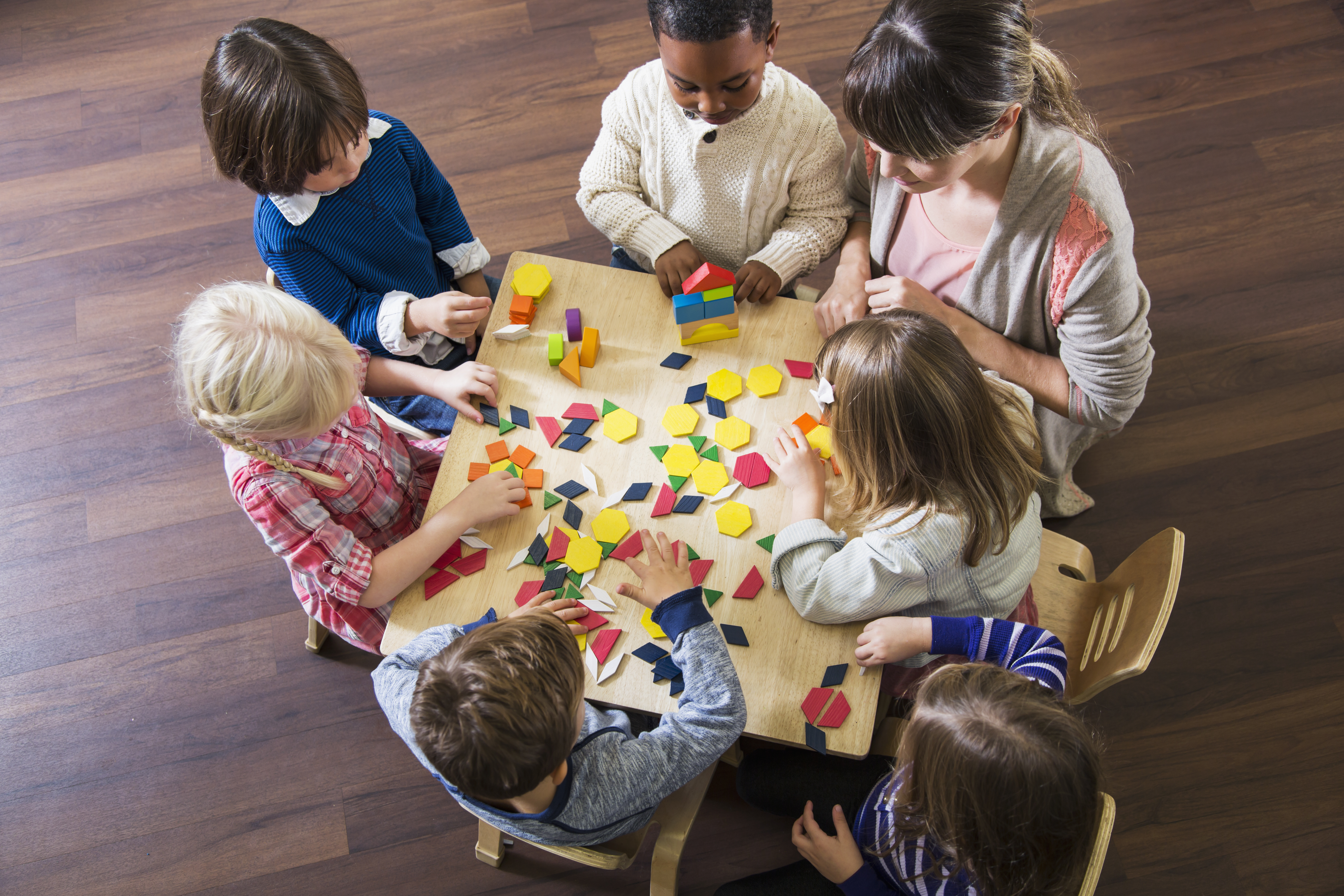 Teacher with preschoolers playing with colorful shapes
