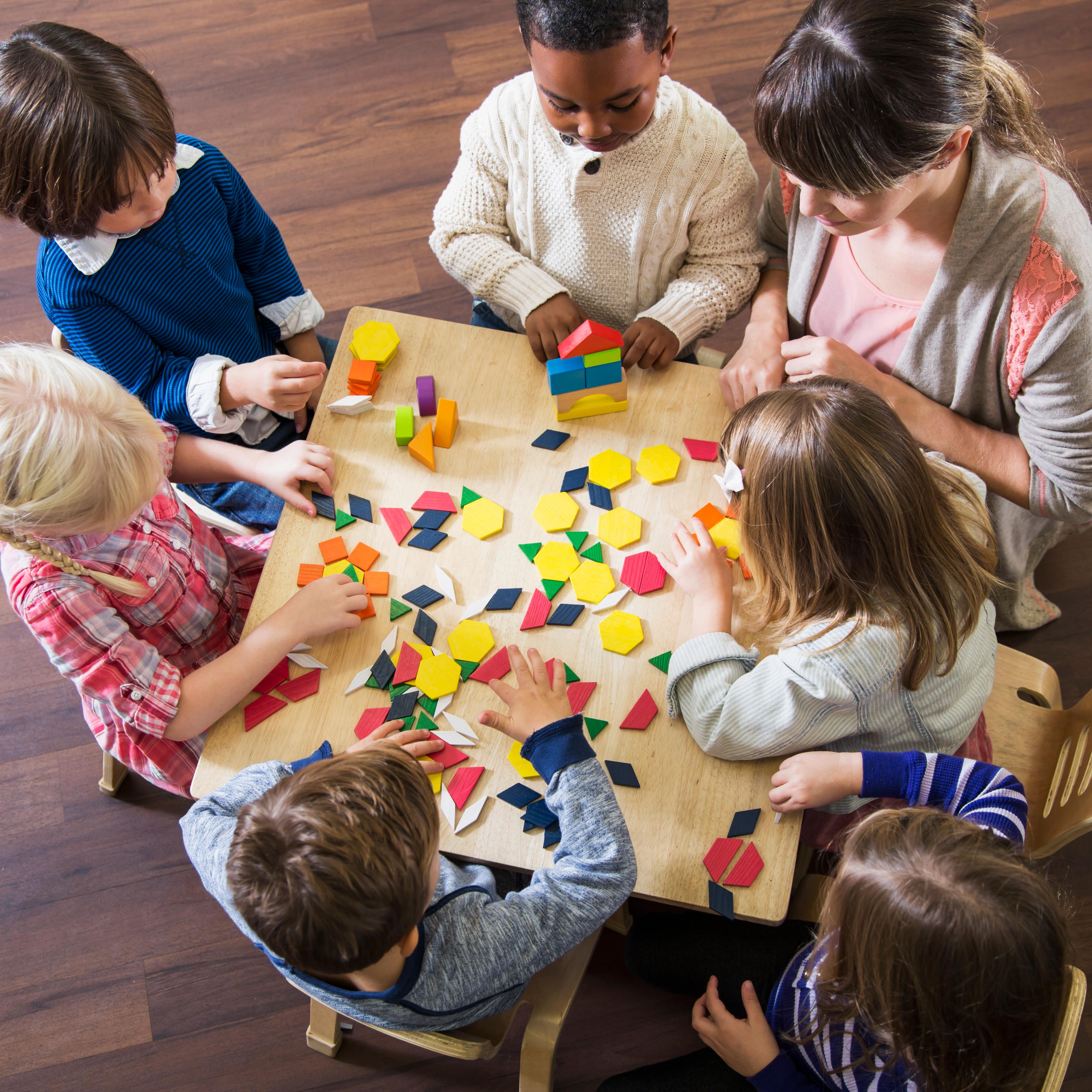 Teacher with preschoolers playing with colorful shapes