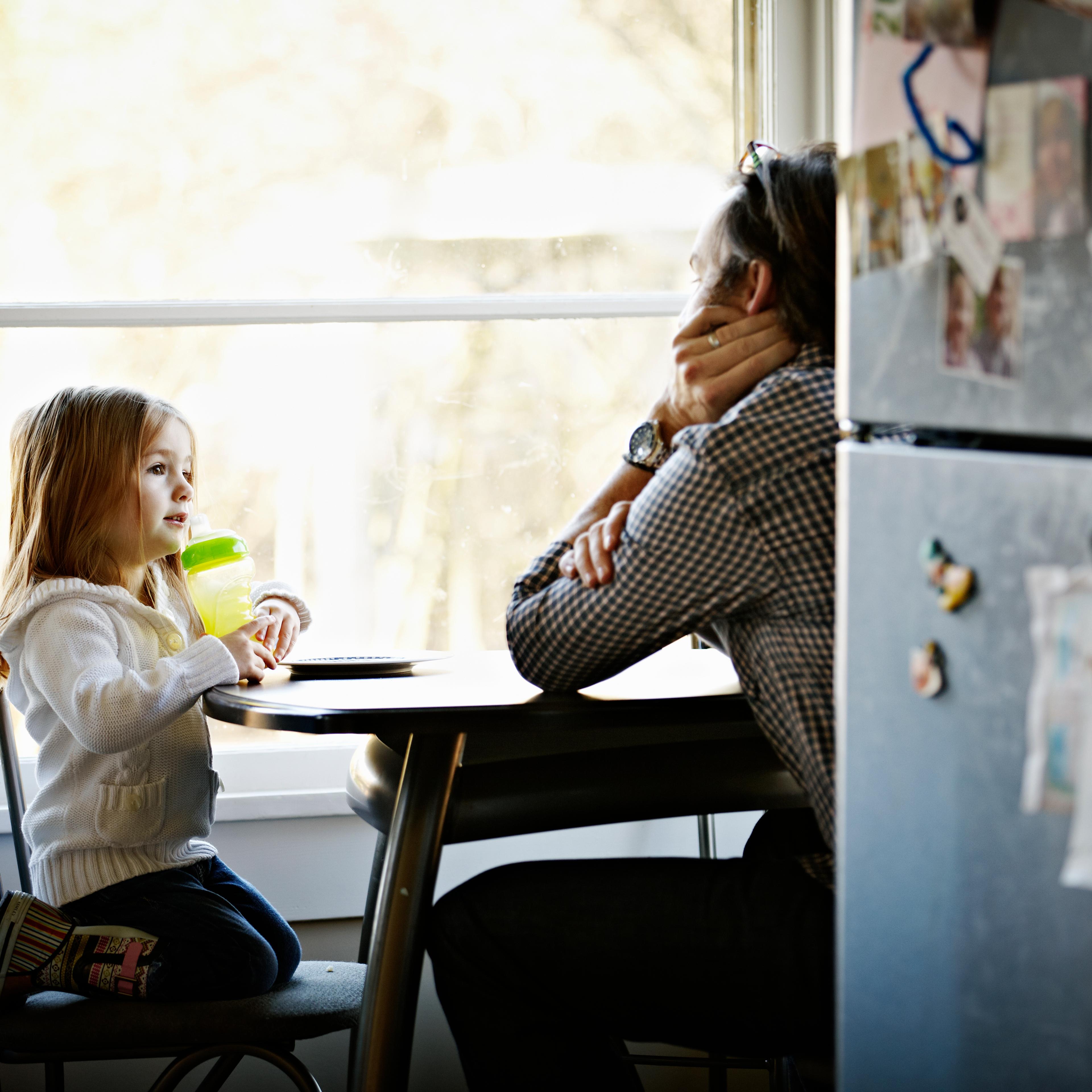 Father and daughter sitting at table in kitchen