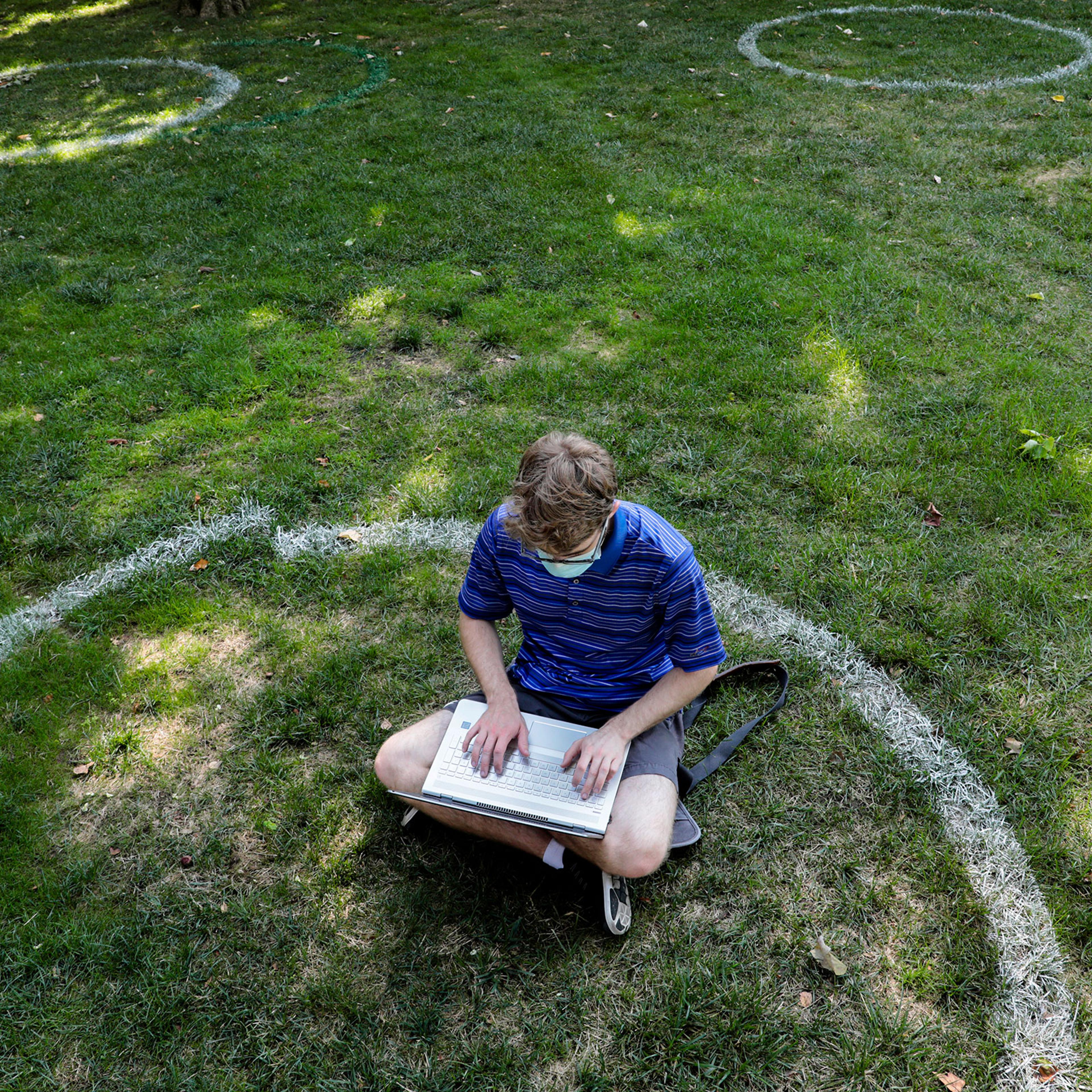 Logan Armstrong, a Cincinnati junior, works while sitting inside a painted circle on the lawn of the Oval during the first day of fall classes on at Ohio State University