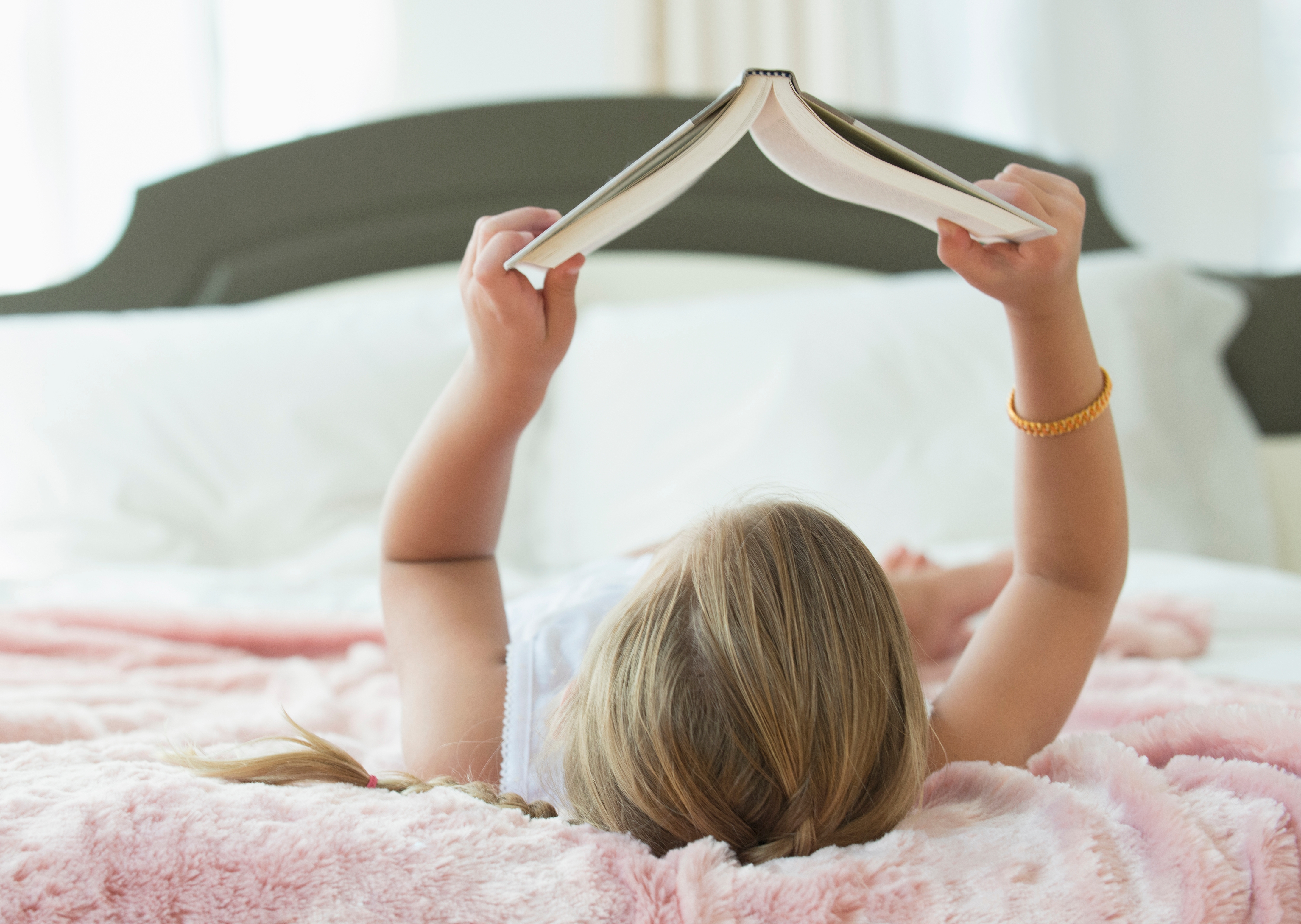Caucasian girl laying on bed reading book