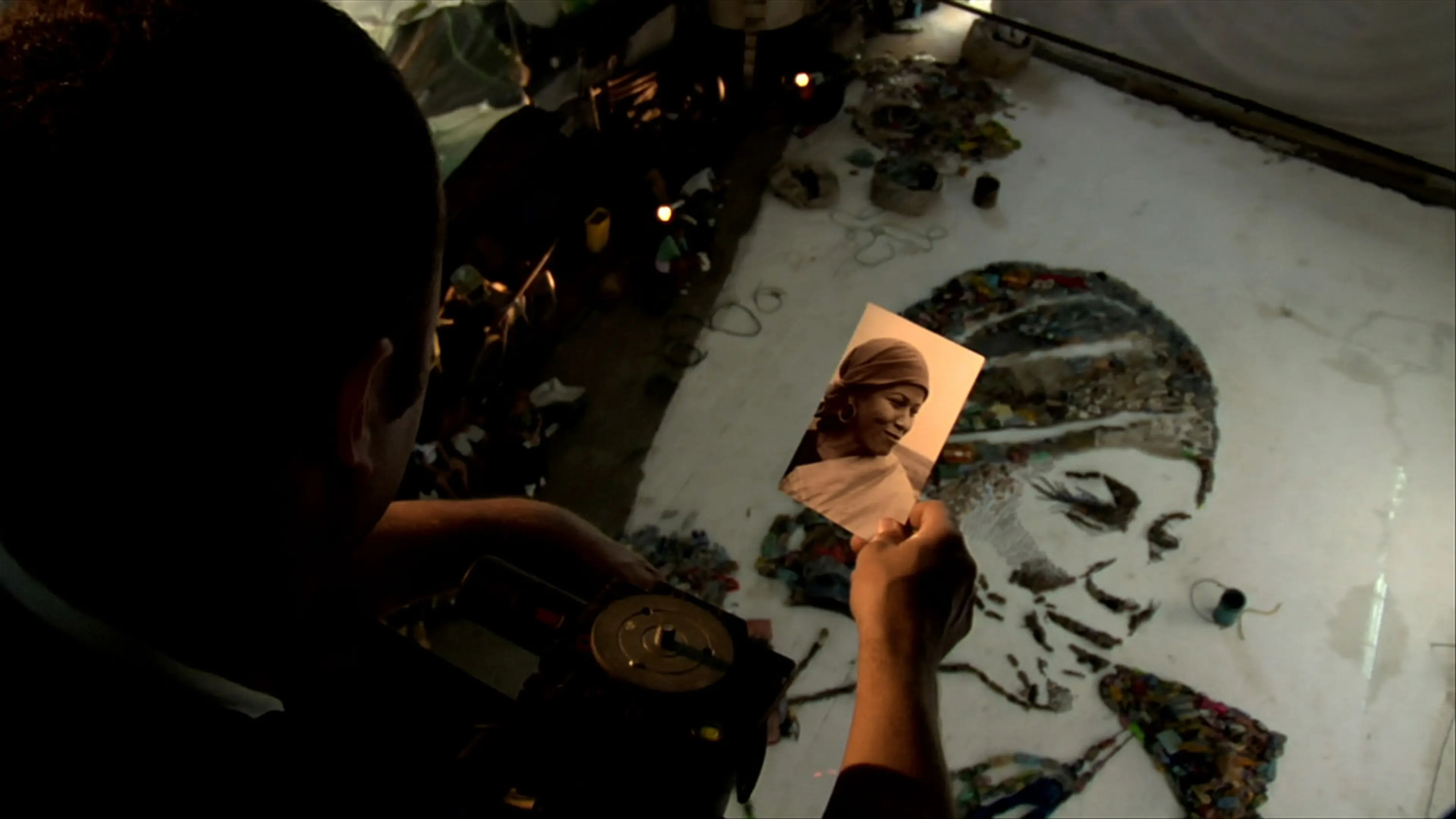 A scene from the film in which Muniz looks at Magna’s photo while her final portrait is created in the studio
