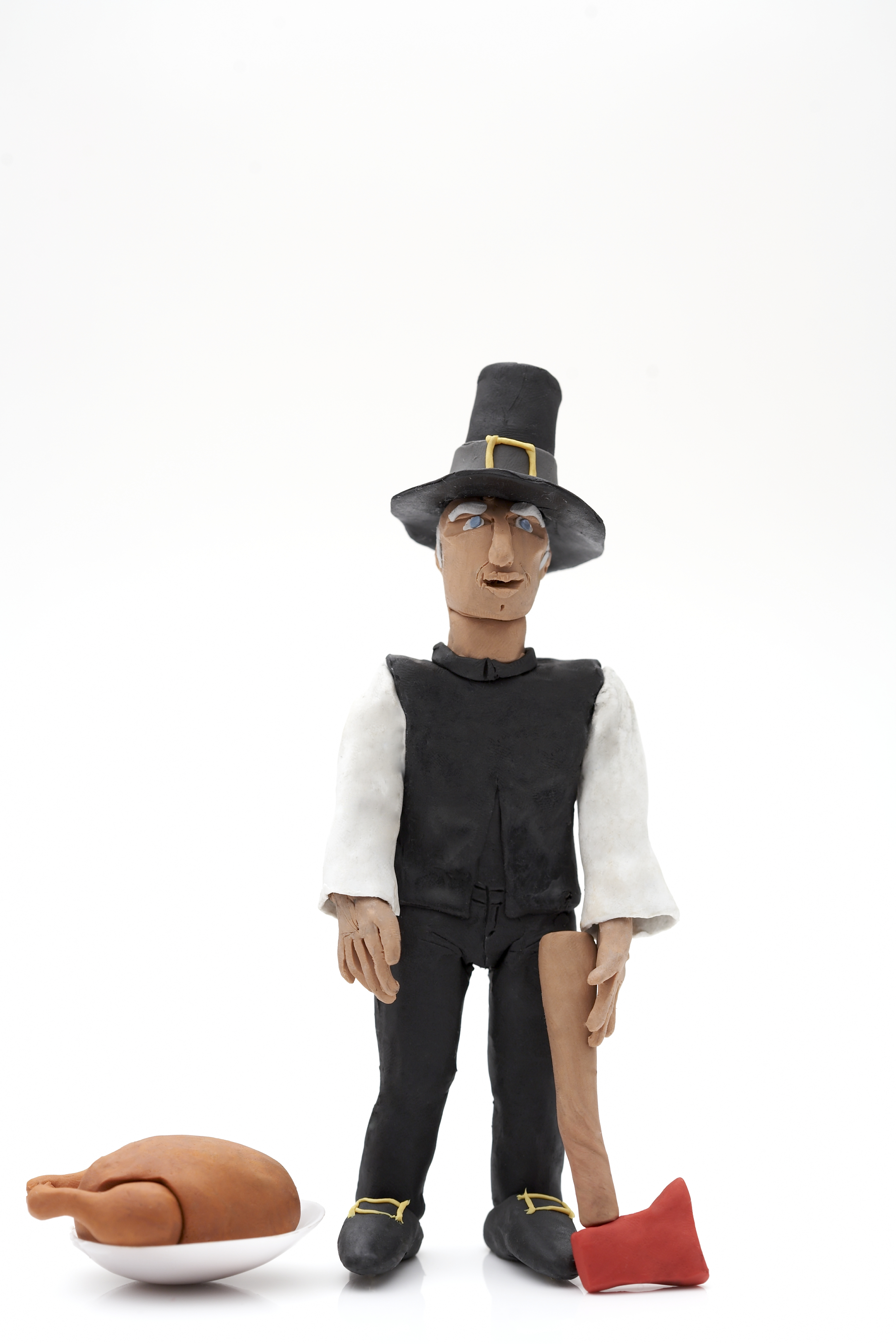 Clay model of Pilgrim figure with turkey and axe on a white background