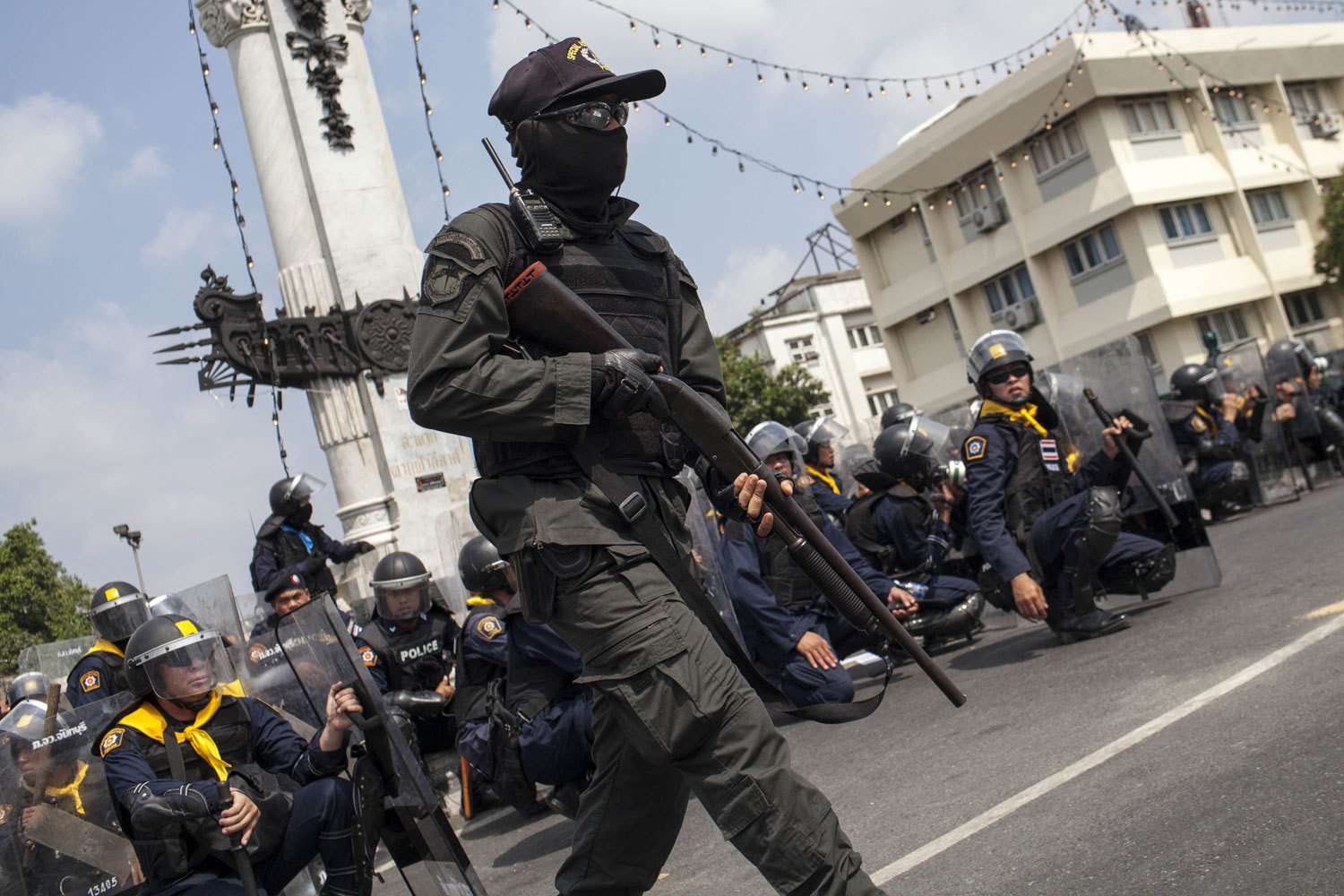 A police officer runs with a shot gun during clashes between police and anti-government protesters during an operation by the Thai government to retake the protester occupied Phan Fa Bridge in Bangkok, on Feb. 18, 2014.