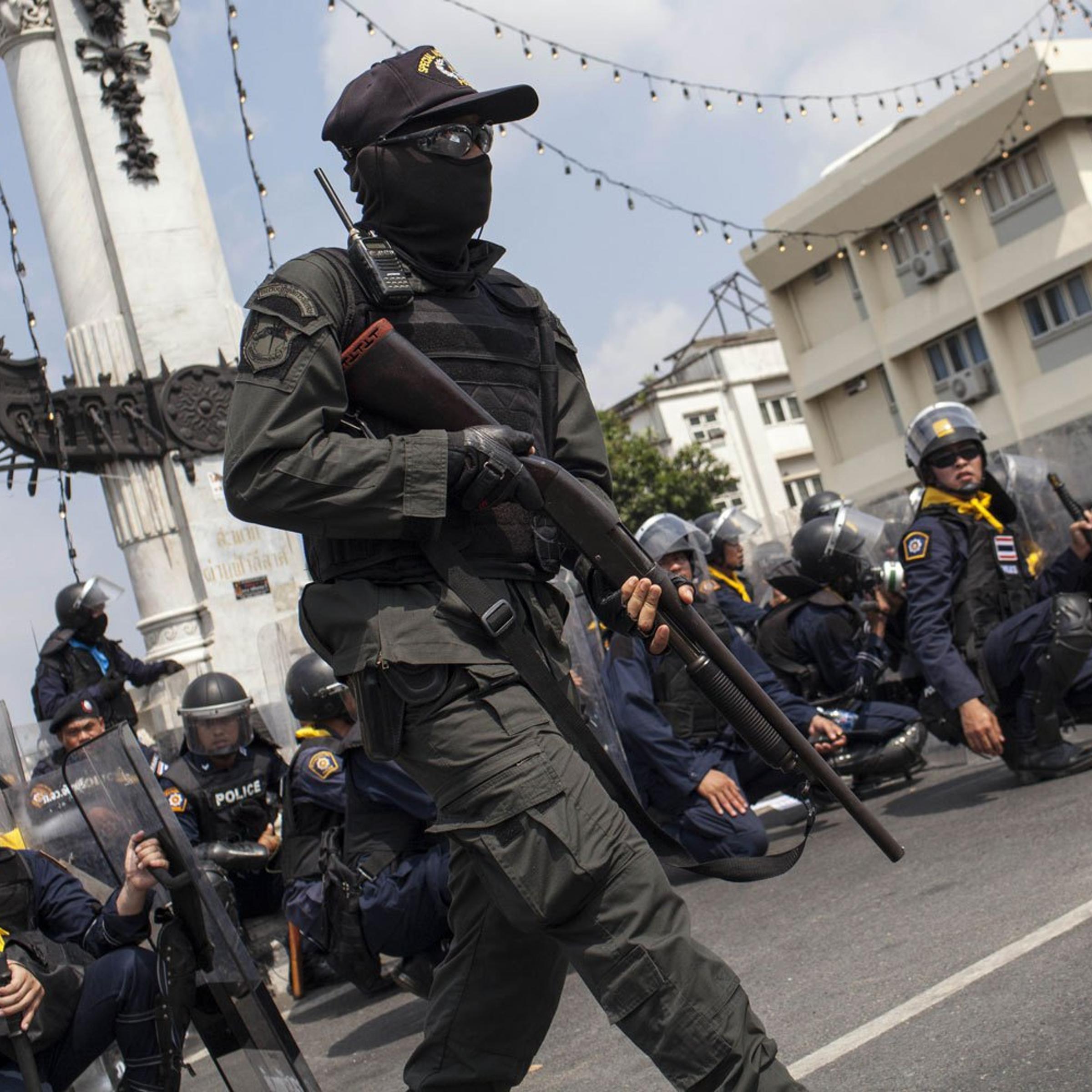 A police officer runs with a shot gun during clashes between police and anti-government protesters during an operation by the Thai government to retake the protester occupied Phan Fa Bridge in Bangkok, on Feb. 18, 2014.