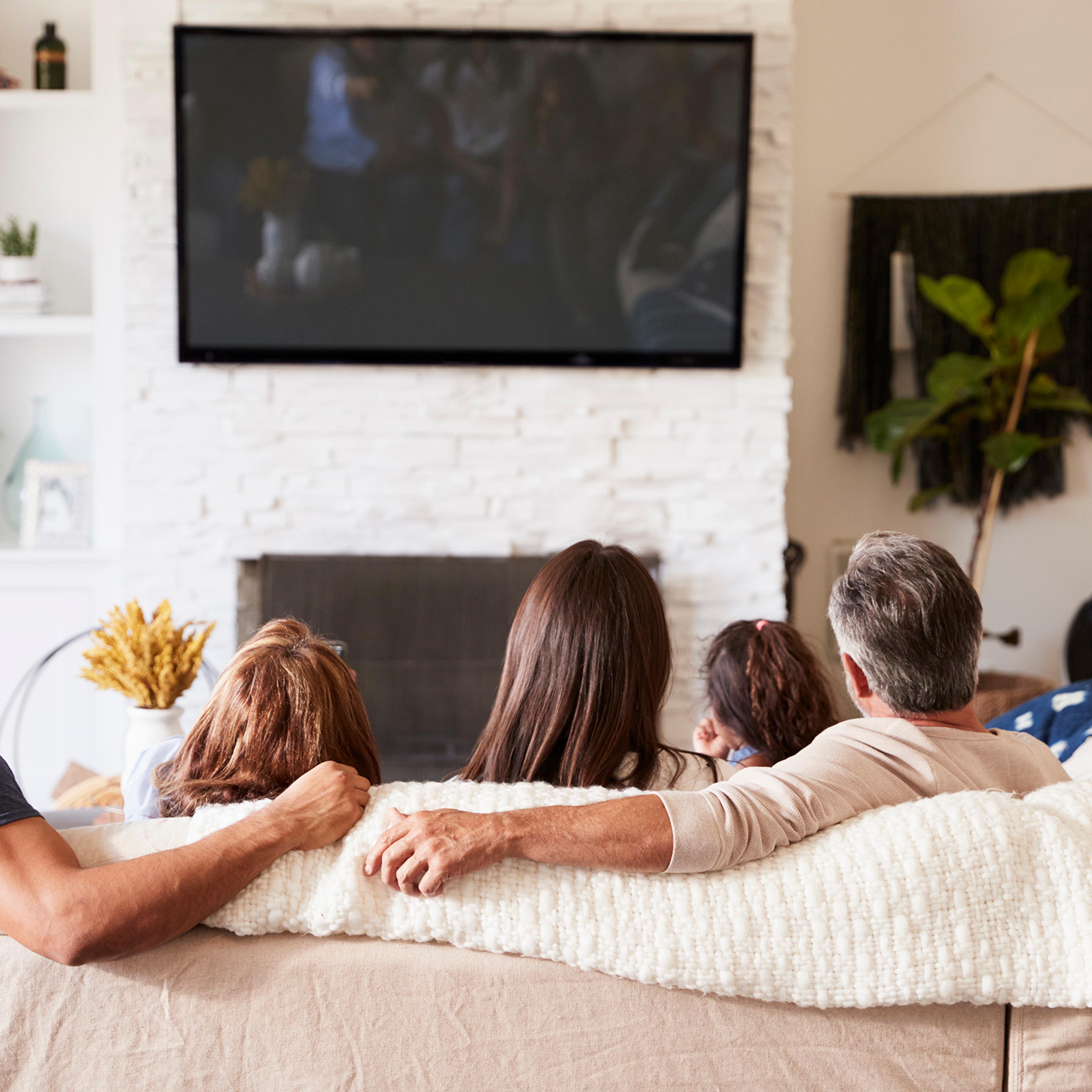 Back view of three generation Hispanic family sitting on the sofa watching TV