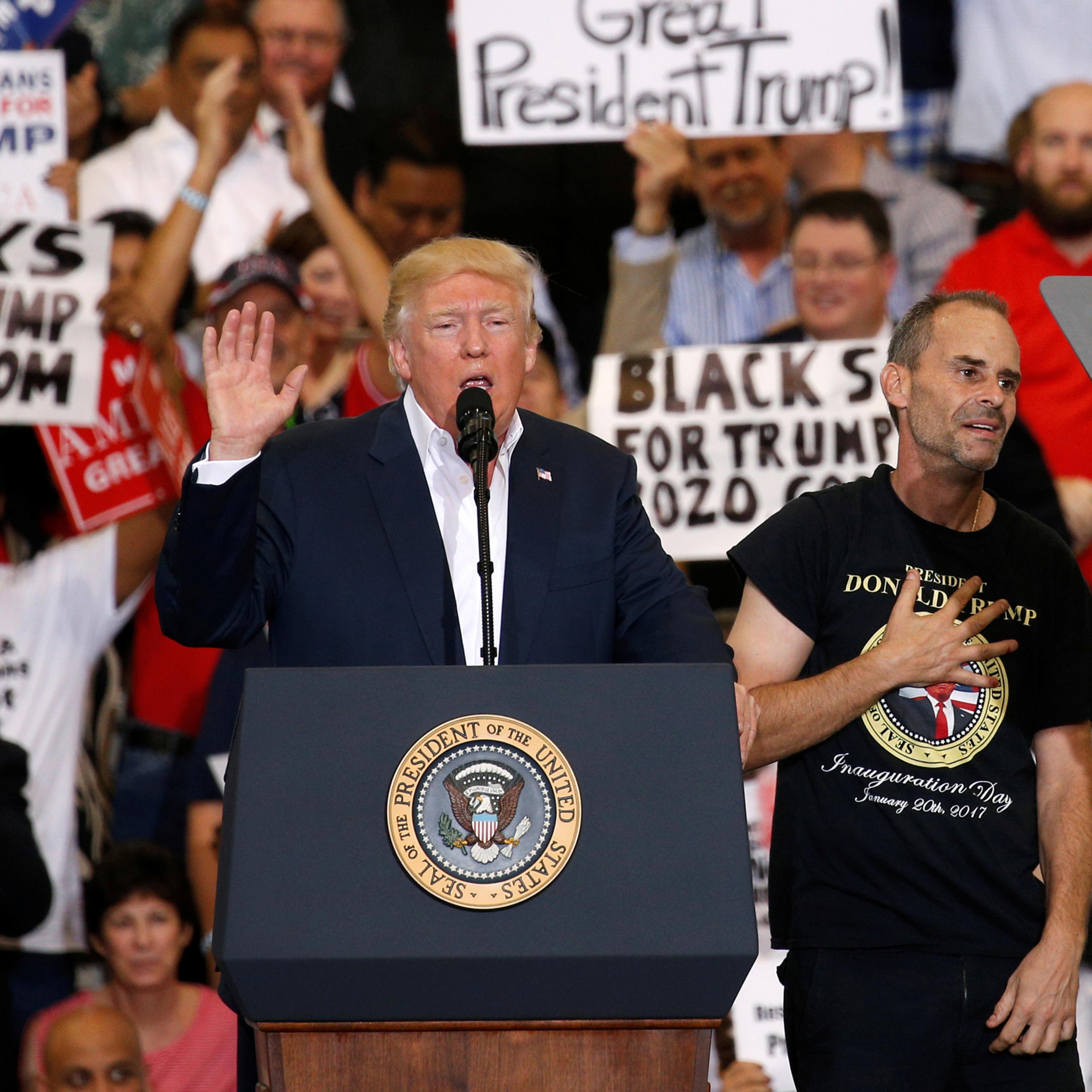Trump holds a supporter invited onstage by U.S. President Donald Trump puts his hand to his chest during a "Make America Great Again" rally at Orlando Melbourne International Airport in Melbourne, Florida, U.S. February 18, 2017. REUTERS/Kevin Lamarque -