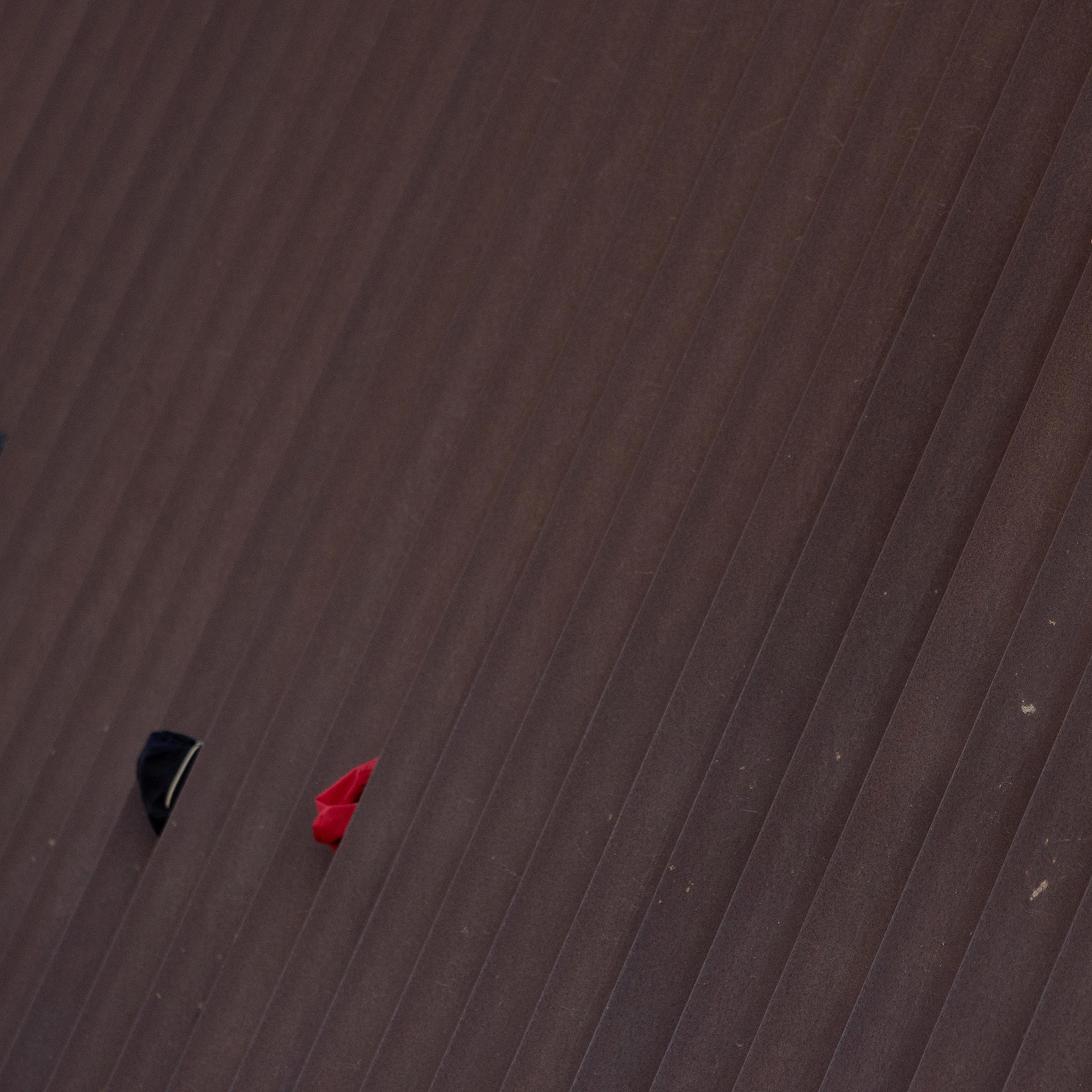 The hands of asylum seeking migrant children from Central America are seen holding the border wall as they await to be transported to a processing center by U.S. Border Patrol agents in Penitas, Texas, on March 17