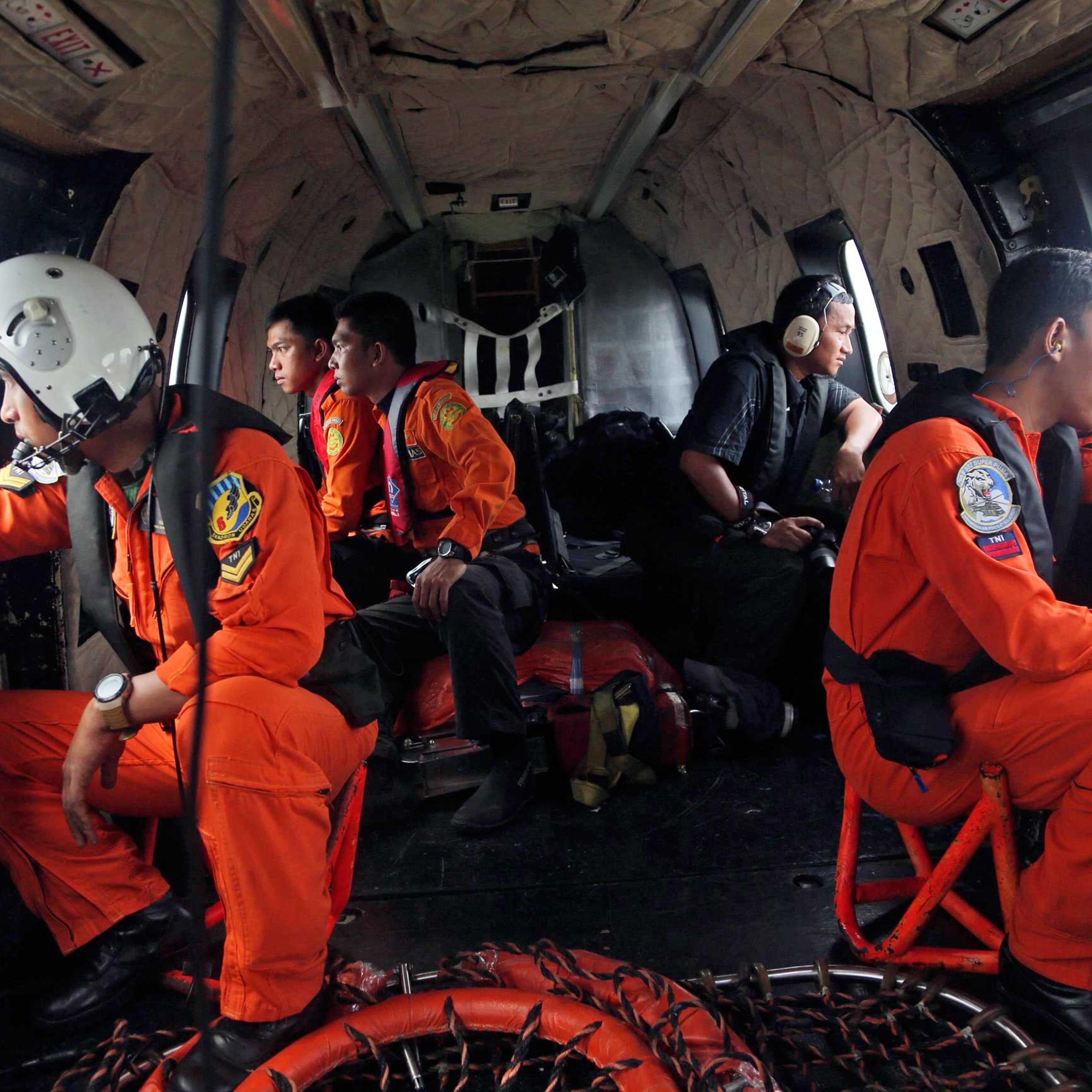 Crewmembers of an Indonesian Air Force NAS 332 Super Puma helicopter look out of the windows during a search operation for the victims and wreckage of AirAsia flight QZ 8501 over the Java Sea