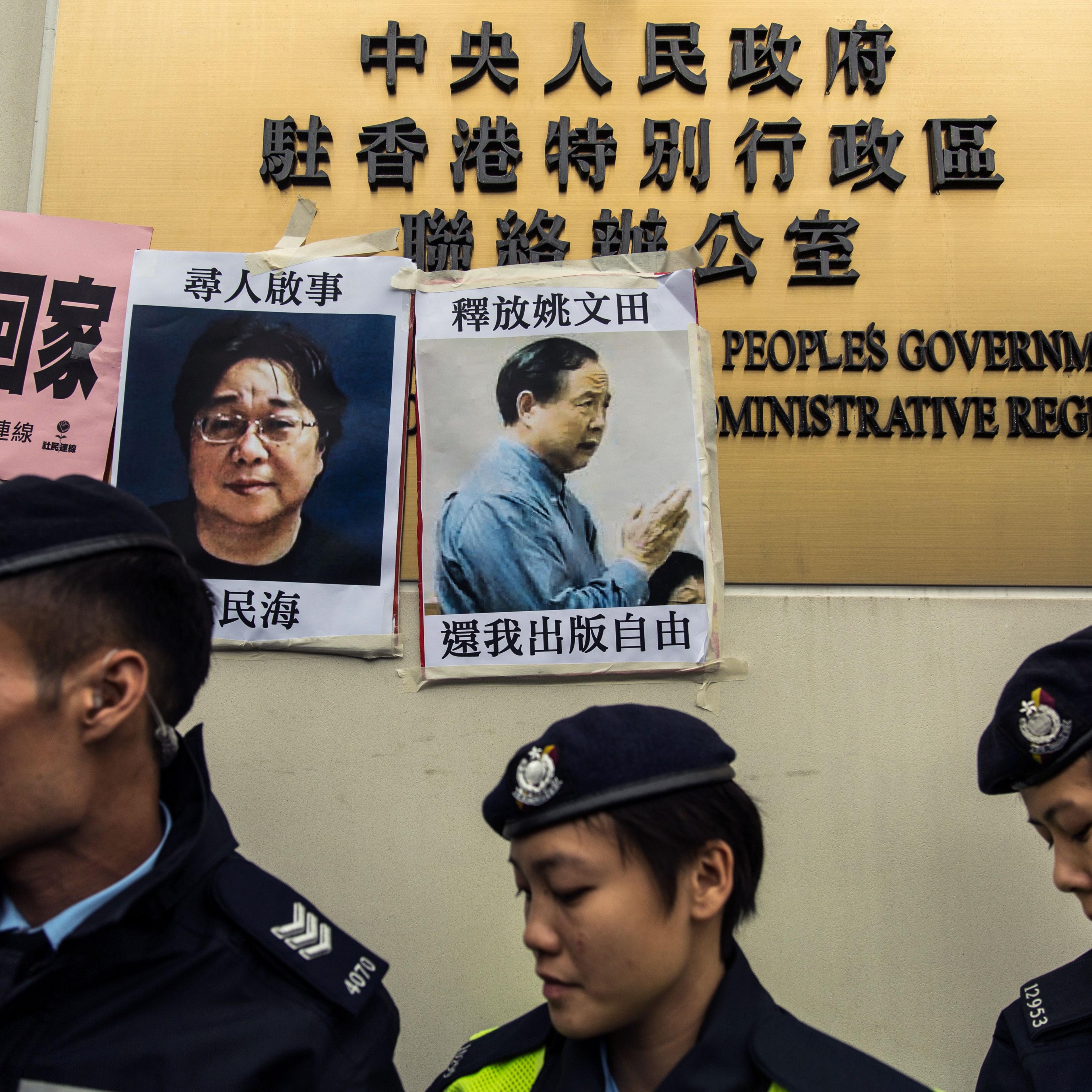 Police walk past missing person notices of Gui Minhai, seen on the left, one of five missing booksellers from the Mighty Current publishing house and Yau Wentian, a Hong Kong publisher who was last year jailed for 10 years while preparing to release a bo