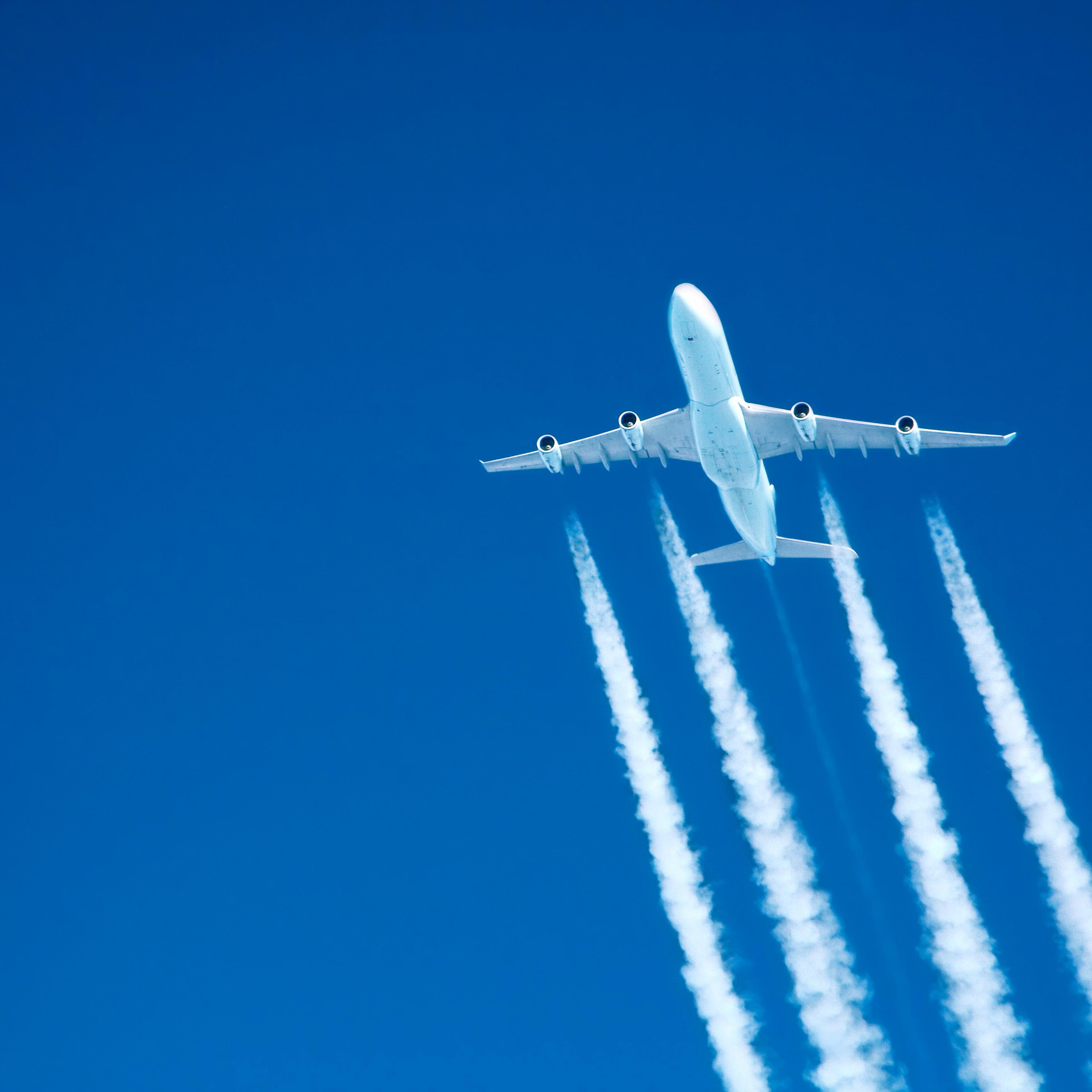 contrails streaming from a jumbo jet on blue sky at altitude