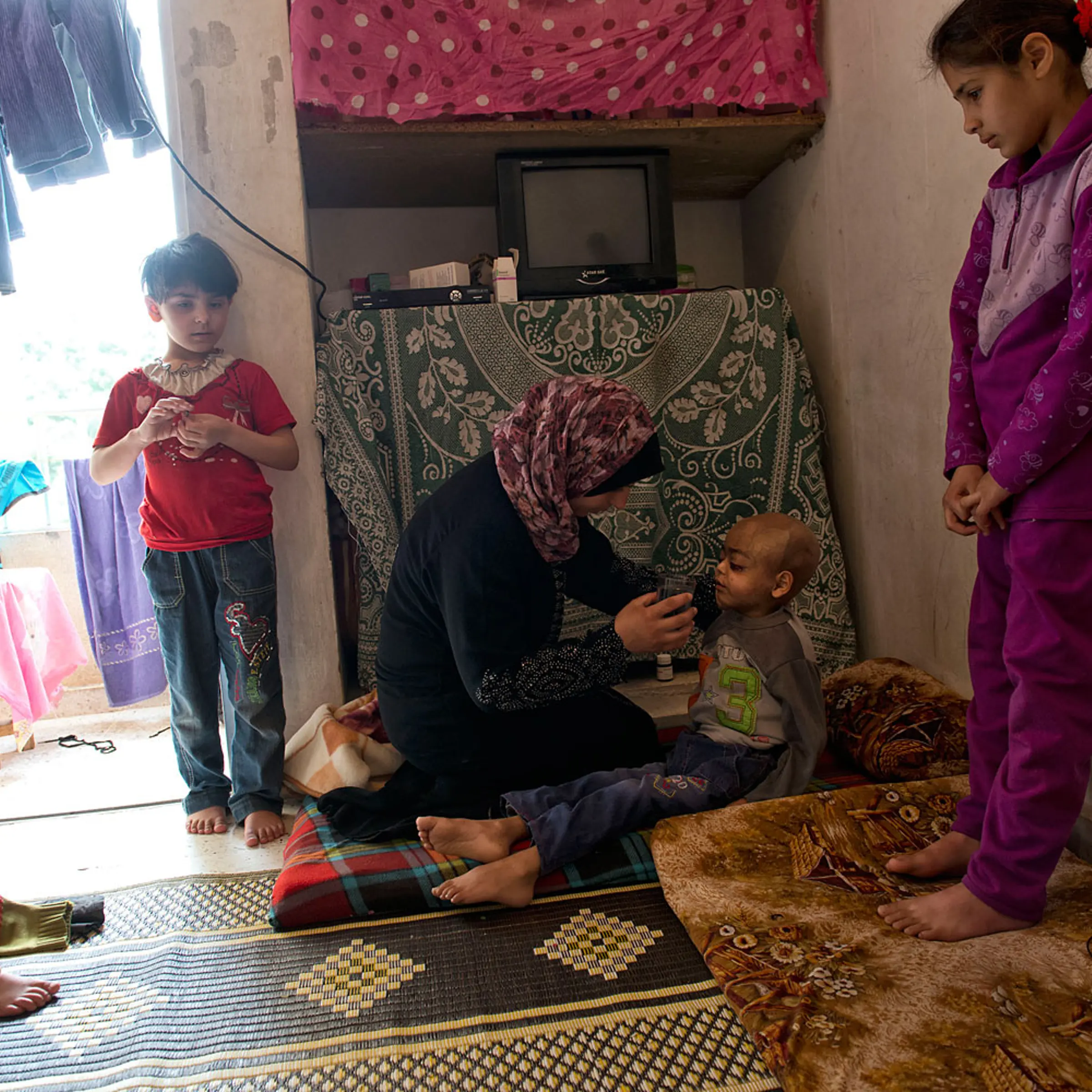 Feryal Delly, a Syrian refugee, gives water to her 4-year-old son Zacharia on March 9. Zacharia, who suffers from a brain tumor, lives with his family in a rented apartment in Halt, north of Beirut.
