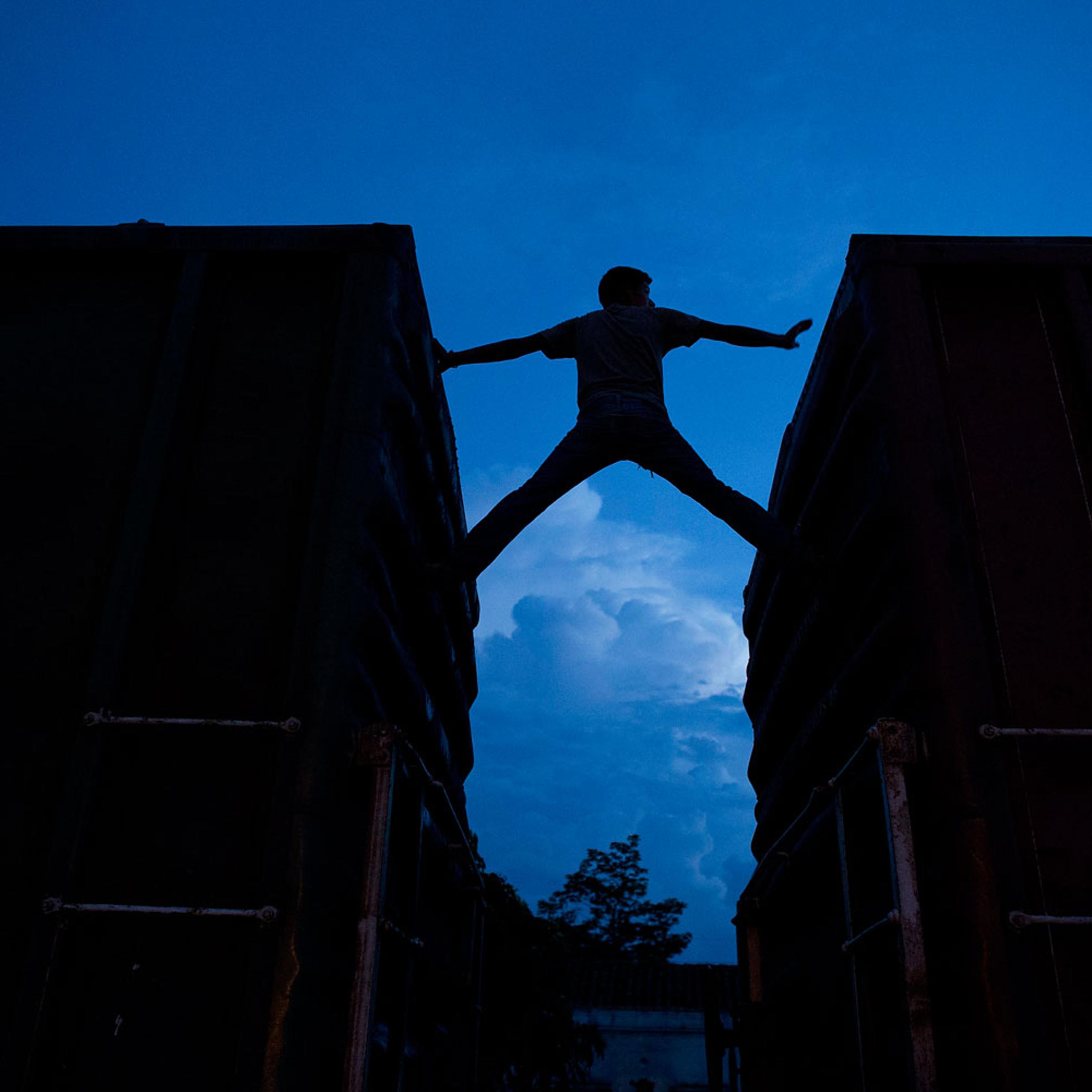 A Central American migrant practices scaling parked boxcars as he awaits the arrival of a northbound freight train in Arriaga, Mexico, on June 19, 2014.