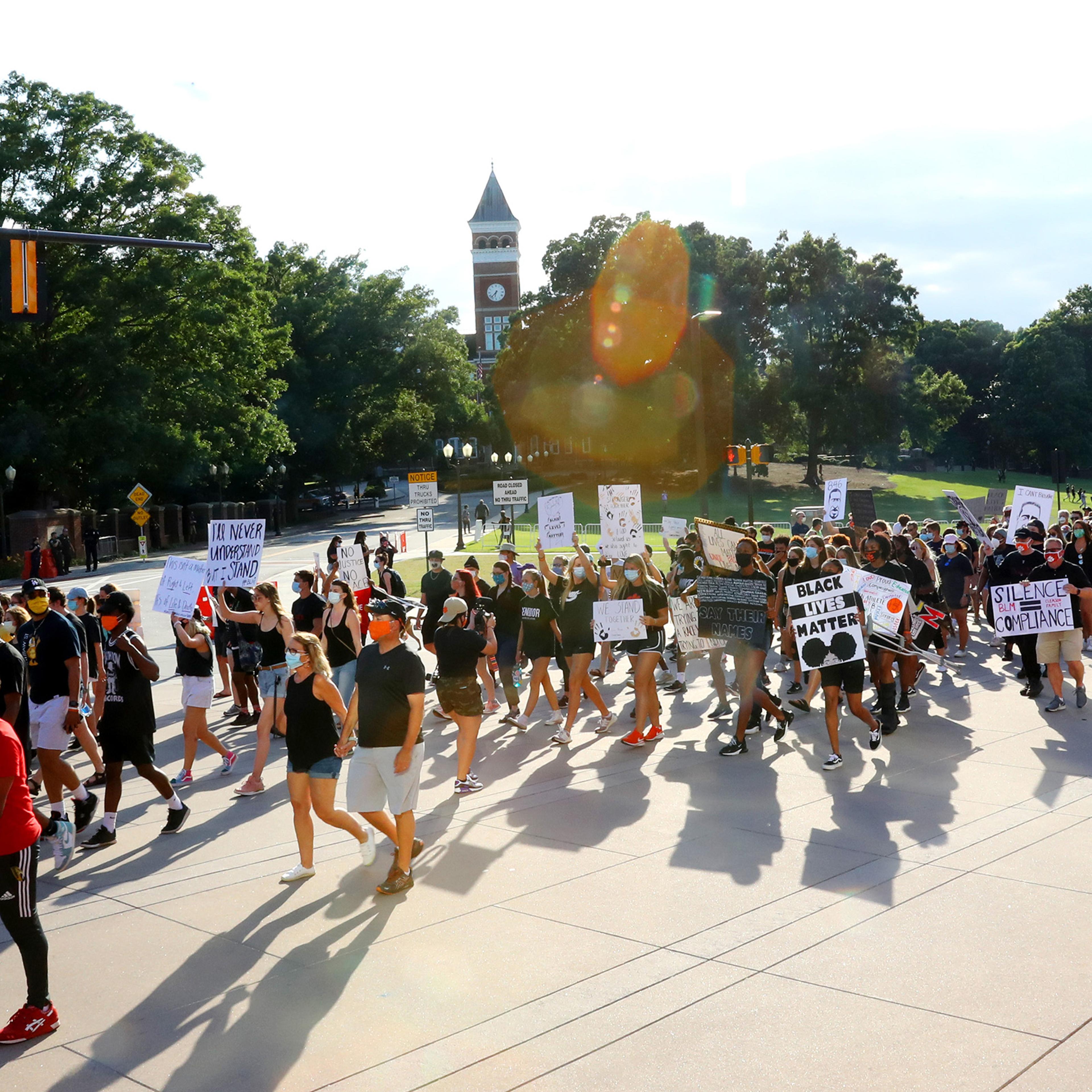 Clemson University football players lead a "March for Change" protest past Tillman Hall on June 13 in Clemson, South Carolina. The Clemson University Board of Trustees voted to strip "Calhoun" from their Honors College name and rename Tillman Hall.
