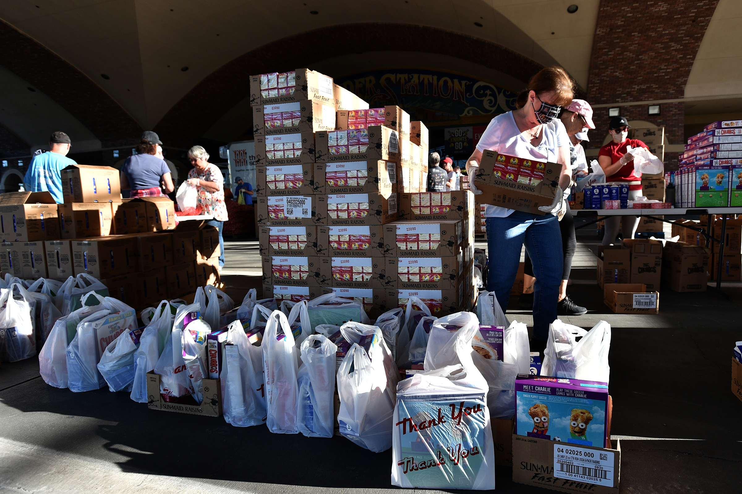 Volunteers prepare groceries to be given out at a drive-thru Three Square Food Bank emergency food distribution site at Boulder Station Hotel & Casino in response to an increase in demand amid the coronavirus pandemic on April 29 in Las Vegas.