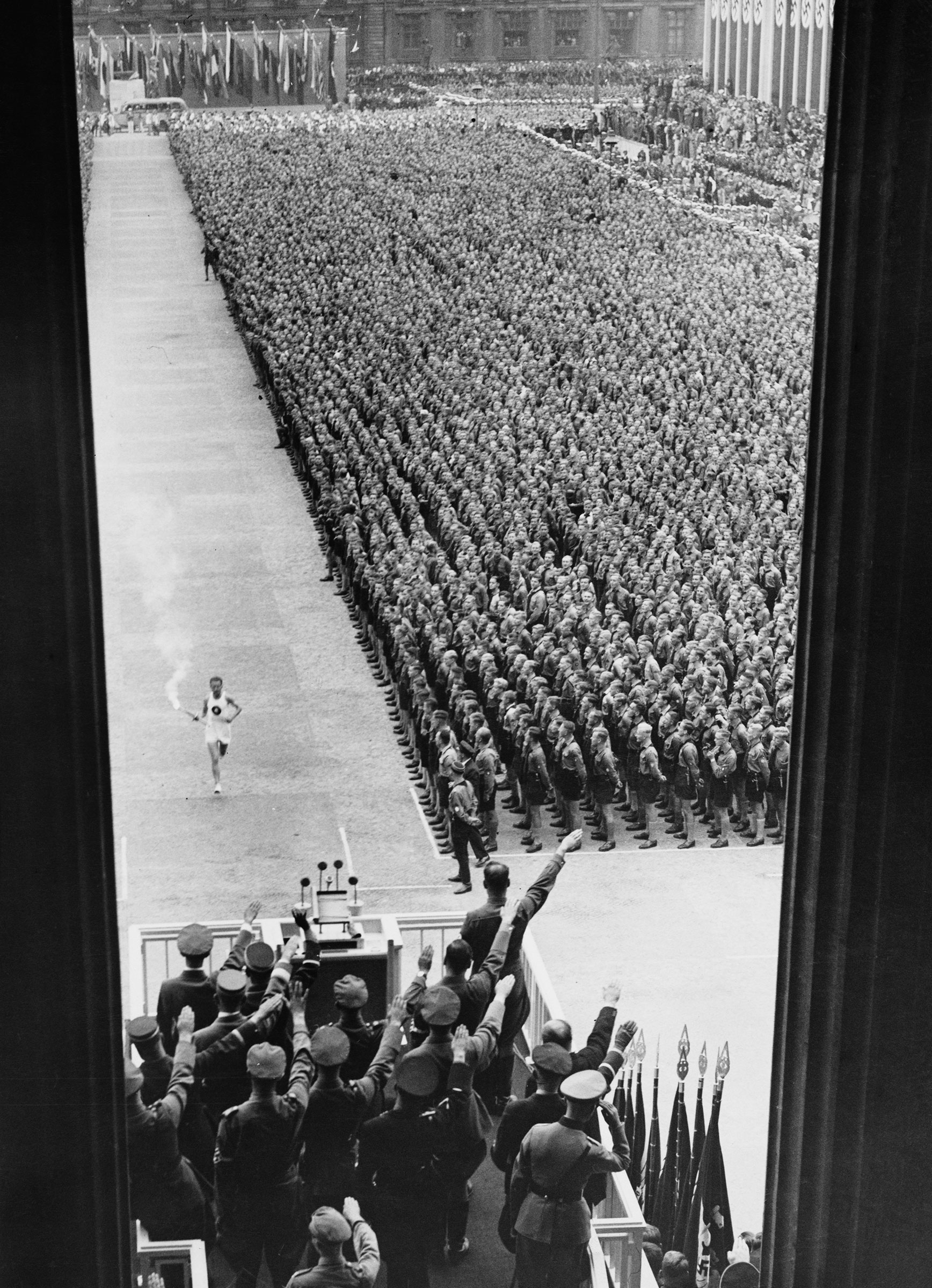 German athlete Fritz Schilgen runs past German army soldiers with the Olympic torch on his way to lighting the Olympic flame at the opening ceremony of the 1936 Summer Olympics at the Olympiastadion in Berlin, Germany, on Aug. 1 1936.