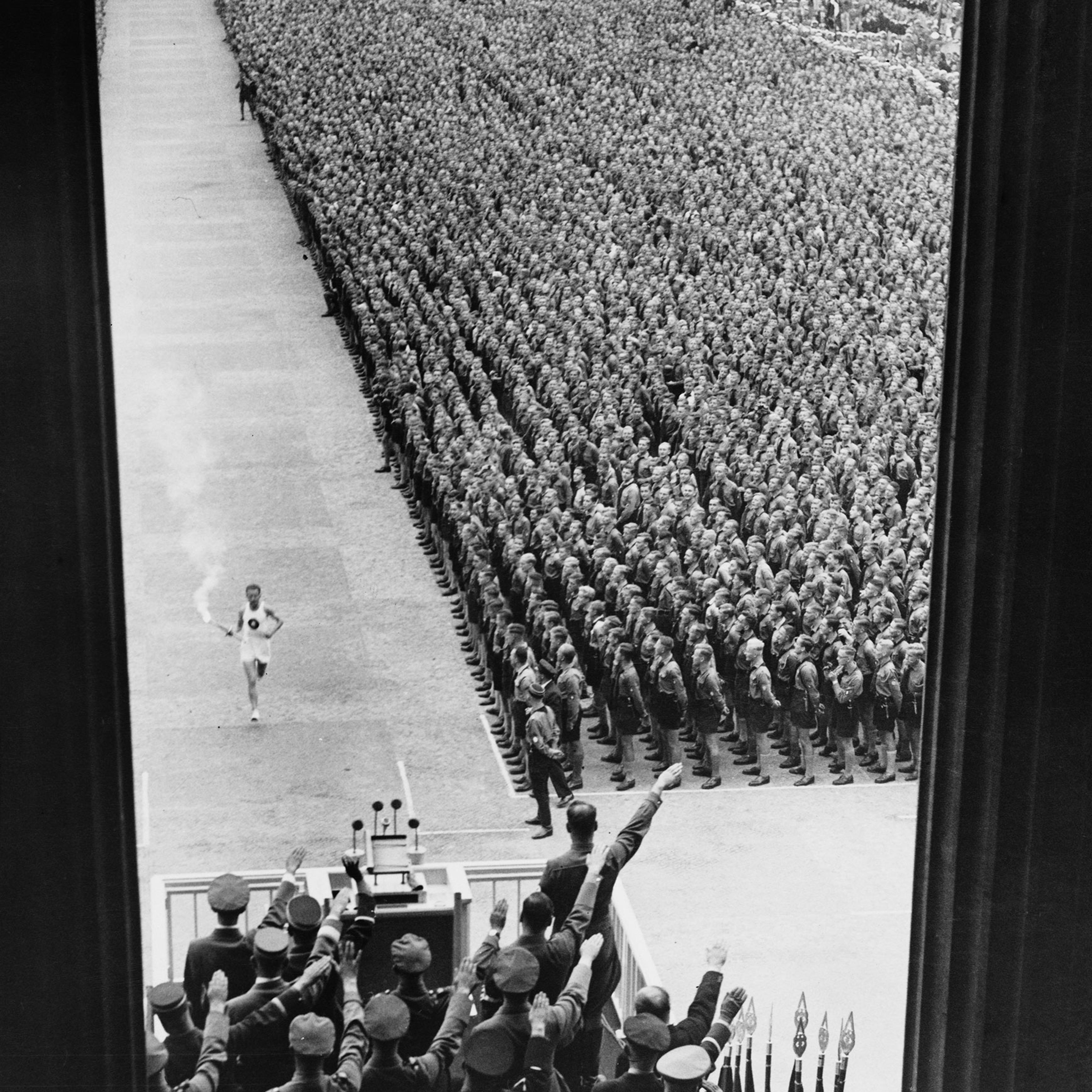 German athlete Fritz Schilgen runs past German army soldiers with the Olympic torch on his way to lighting the Olympic flame at the opening ceremony of the 1936 Summer Olympics at the Olympiastadion in Berlin, Germany, on Aug. 1 1936.