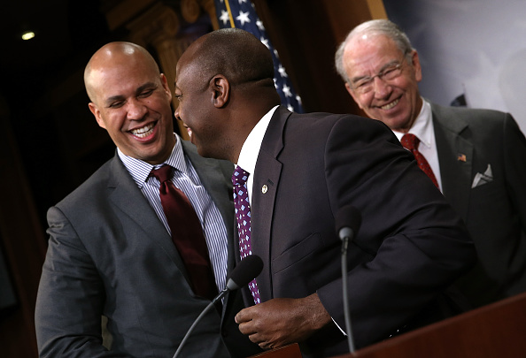 Sen. Corey Booker (L) (D-NJ) hugs Sen. Tim Scott (C) (R-SC) as Senate Judiciary Committee Chairman Sen. Chuck Grassley (R) (R-IA) looks on during a press conference at the U.S. Capitol announcing a bipartisan effort to reform the criminal justice system 