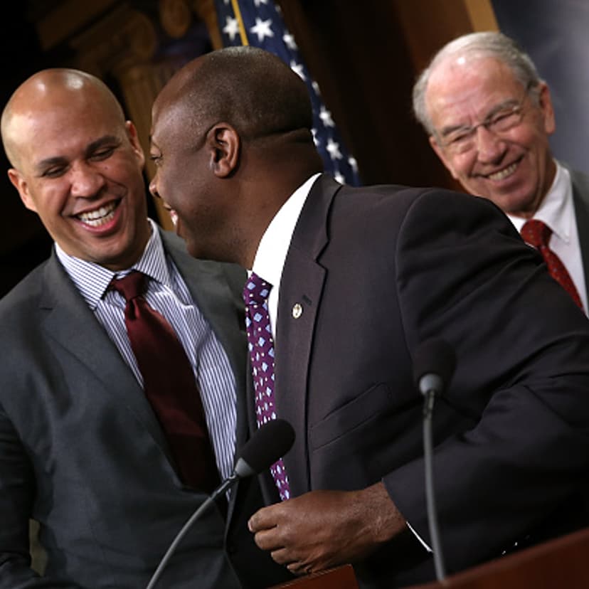 Sen. Corey Booker (L) (D-NJ) hugs Sen. Tim Scott (C) (R-SC) as Senate Judiciary Committee Chairman Sen. Chuck Grassley (R) (R-IA) looks on during a press conference at the U.S. Capitol announcing a bipartisan effort to reform the criminal justice system