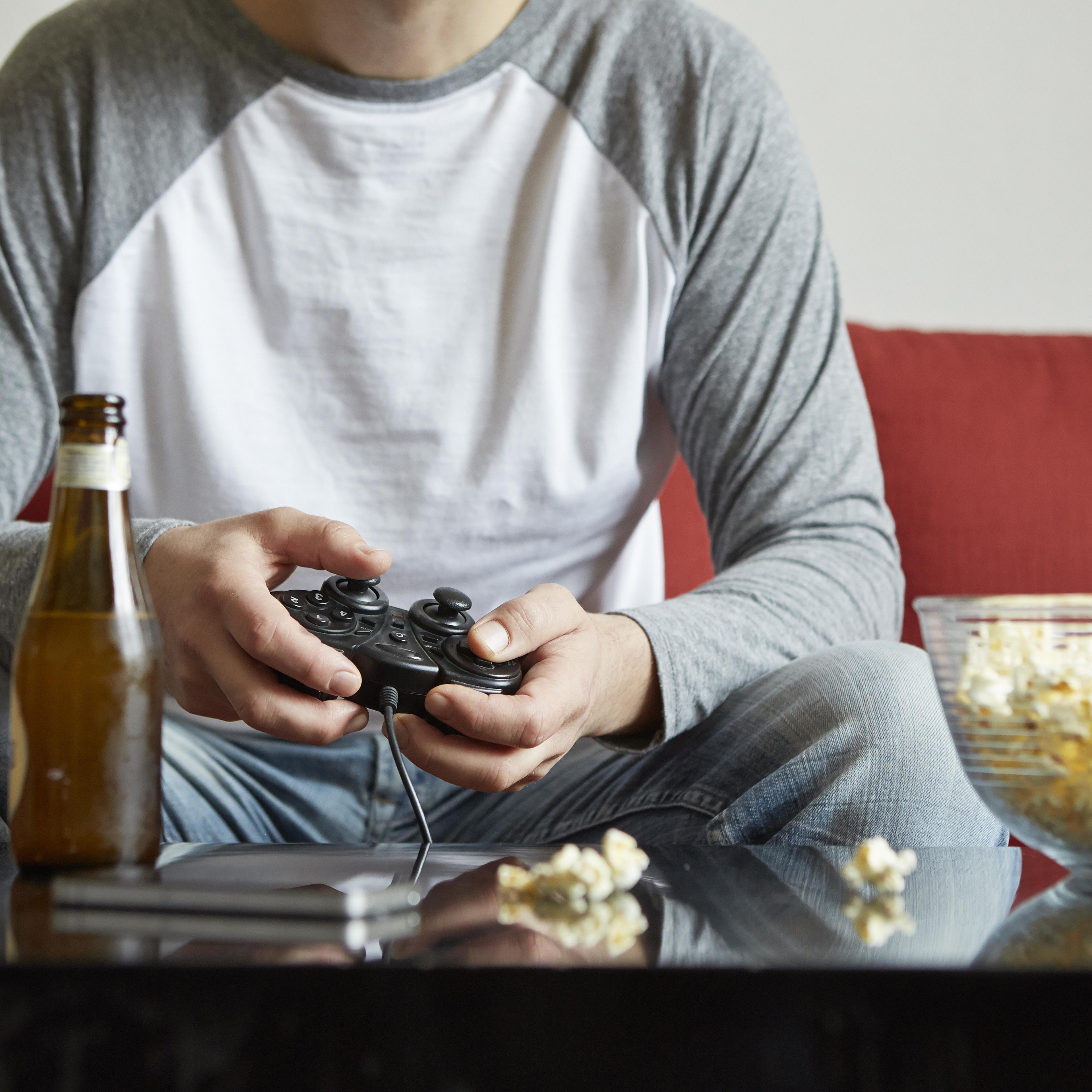 Mid adult man sitting on sofa using computer game control