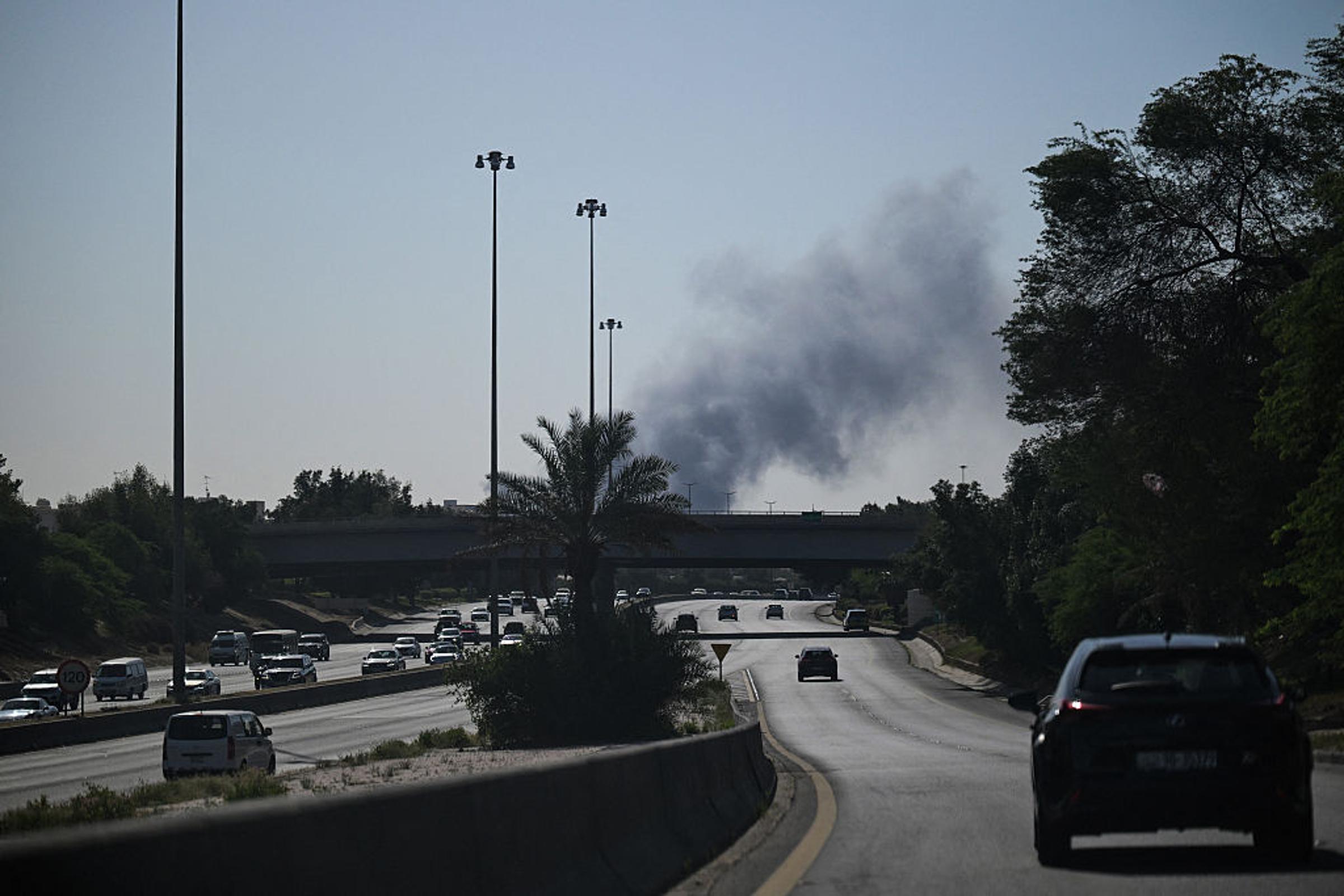 Motorists drive along a street as smoke rises from a reported Iranian strike in the area where the U.S. Embassy is located in Kuwait City on March 2, 2026.