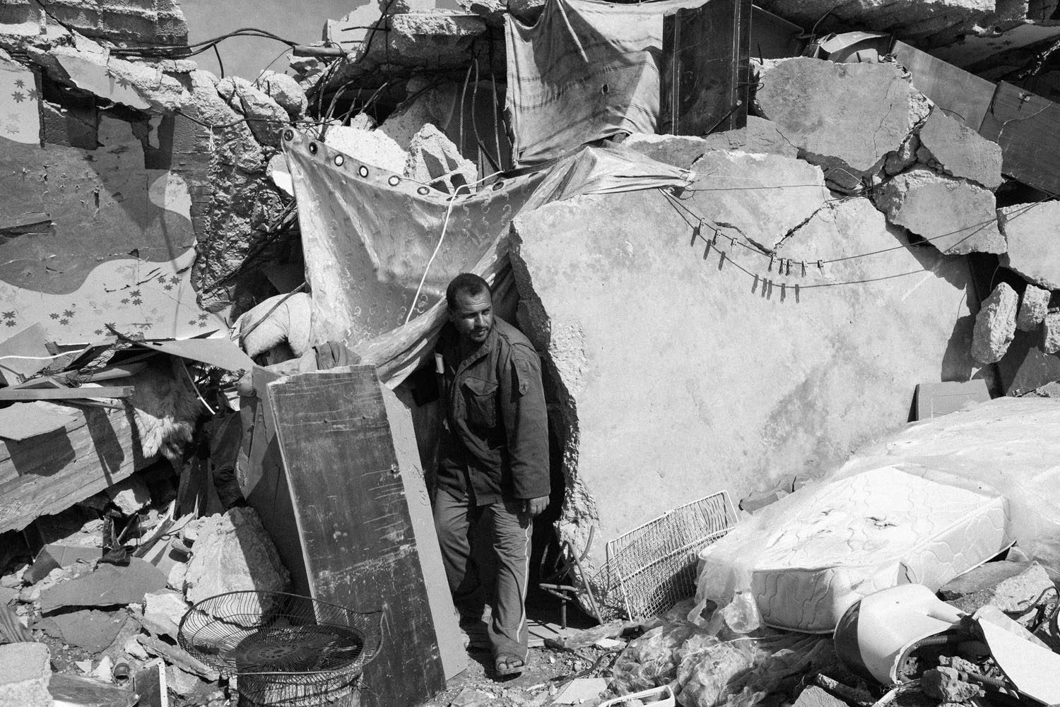 Al Khumaini Msallam Qudiah is seen exiting his rubbled home in Khan Younis, southern Gaza, on Nov. 1st 2014.Al Khumaini and his sons live in the rubbled home, while his wife and daughters live with their relatives. His farmland was bulldozed by Israeli a
