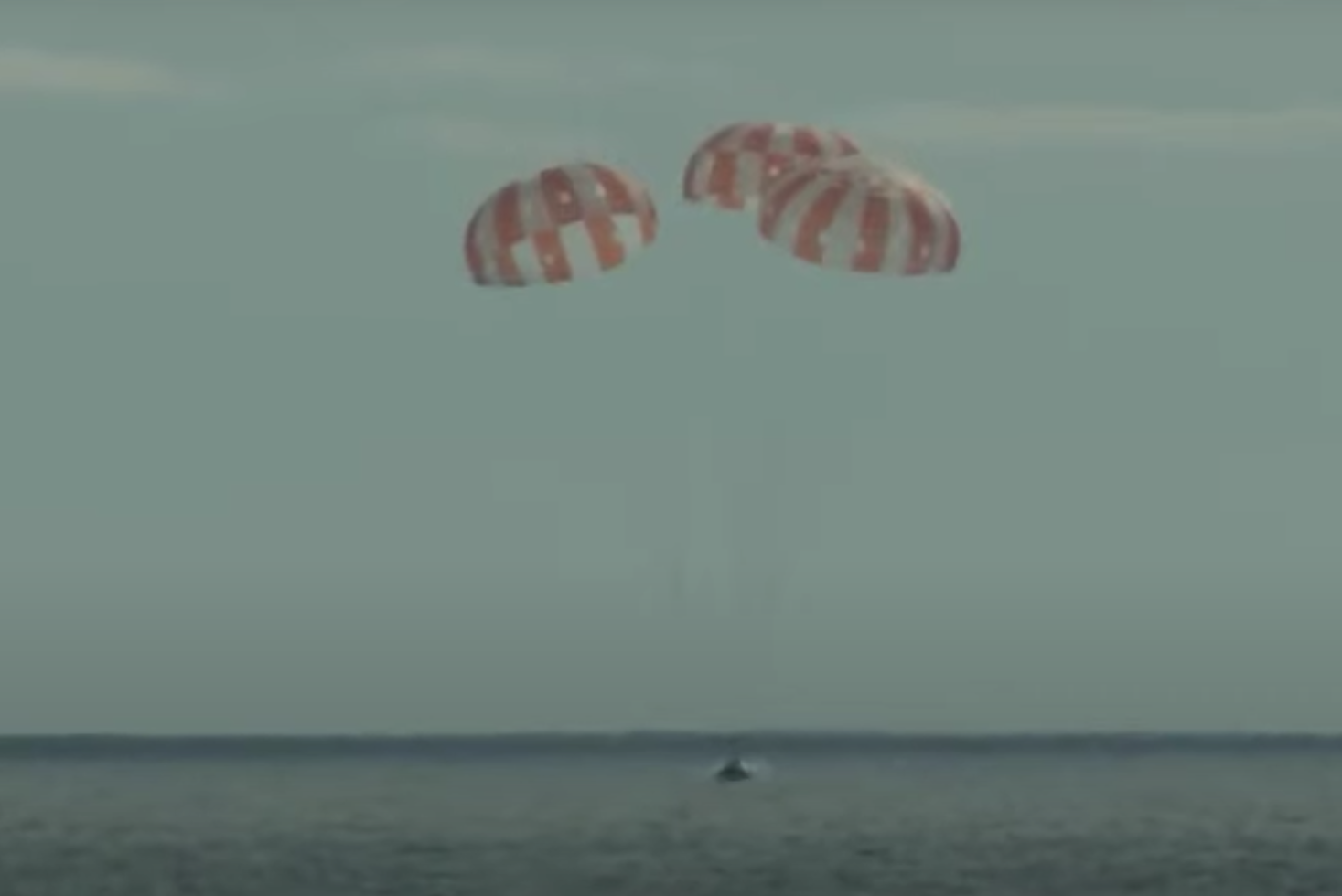 The Orion spacecraft descends under its three main chutes, off the coast of Baja California.