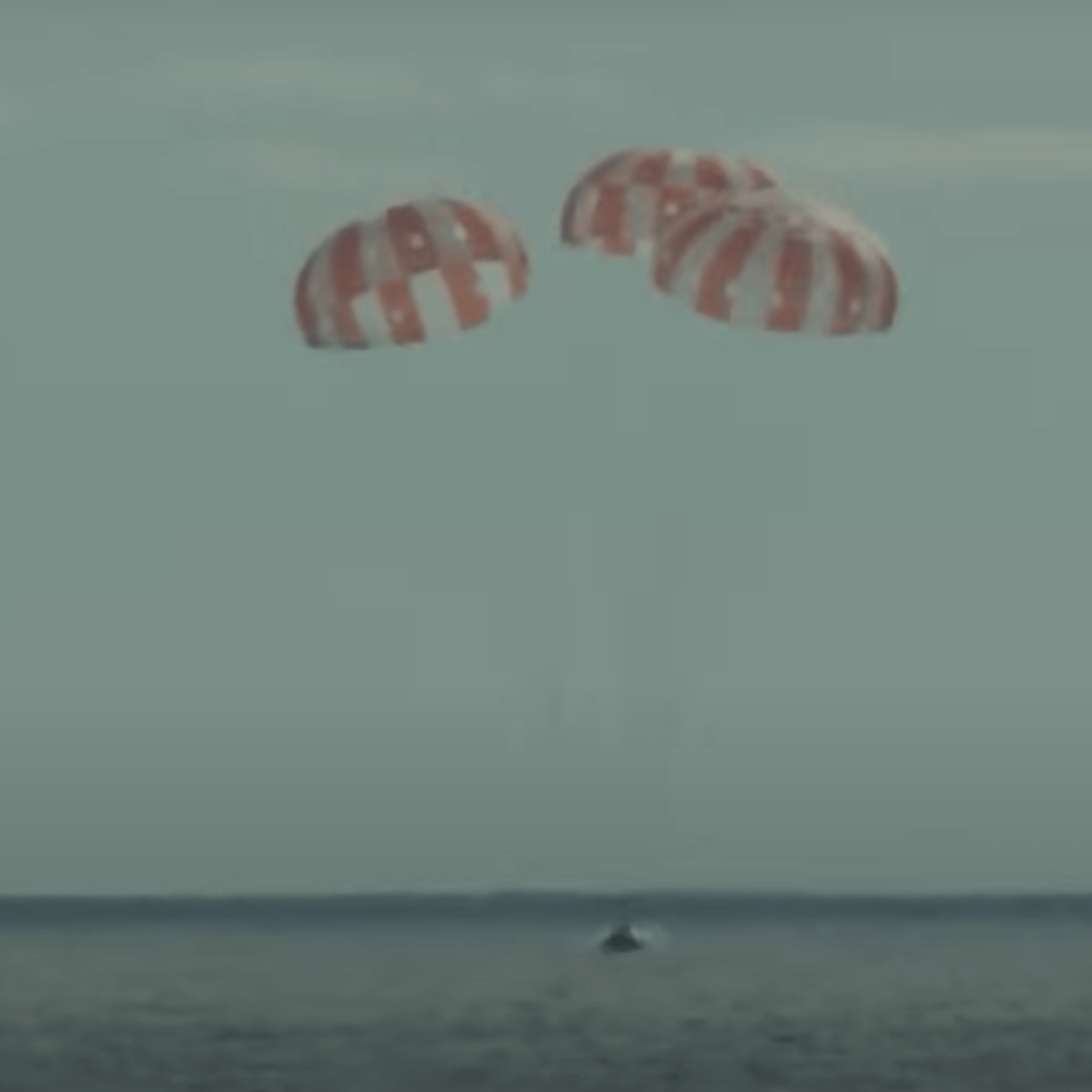 The Orion spacecraft descends under its three main chutes, off the coast of Baja California.