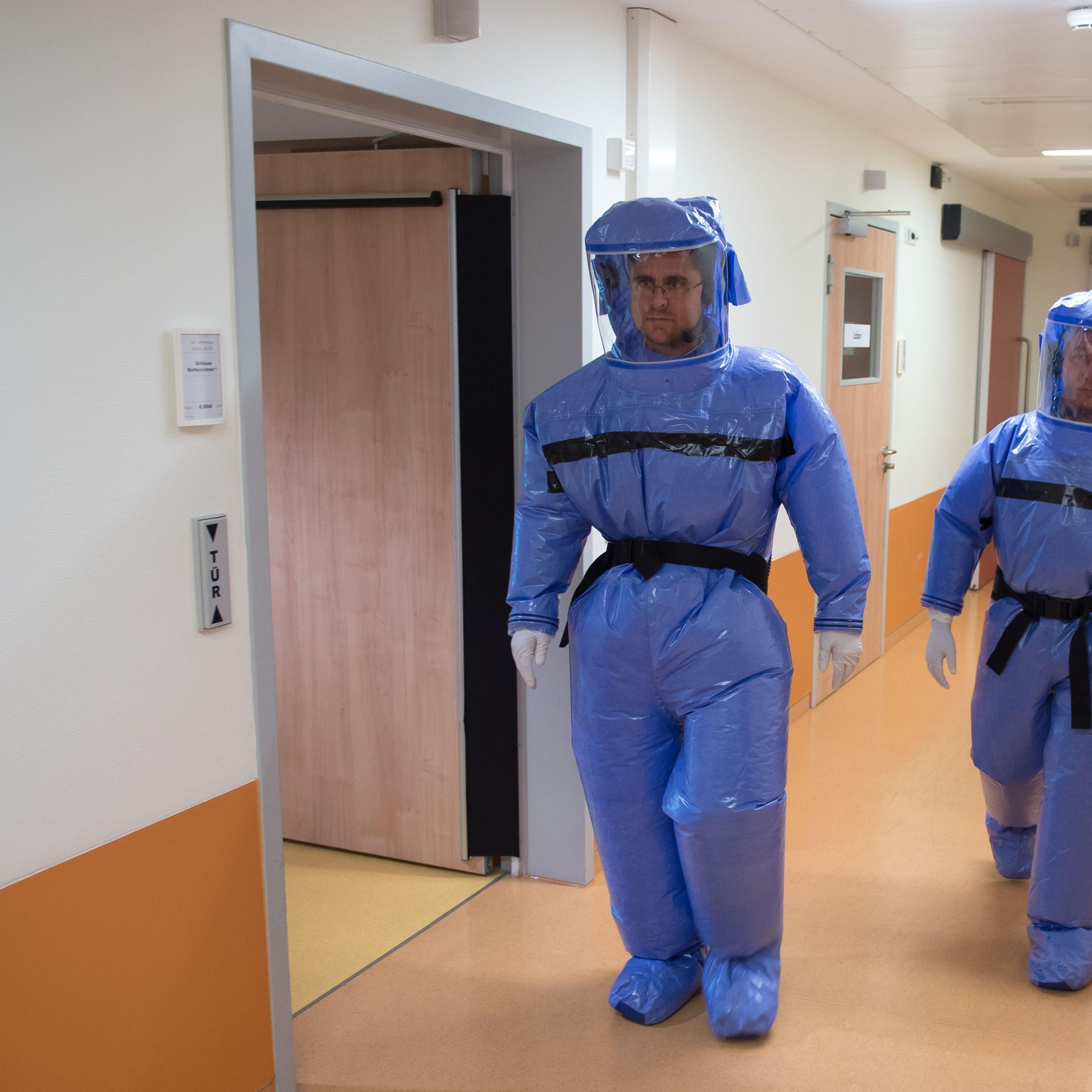 Infectious disease specialist Florian Steiner and quarantine office leader Thomas Klotzkowski wear protective clothing as they demonstrate the proceedings at the ward of Berlin's Charite hospital on August 11, 2014.