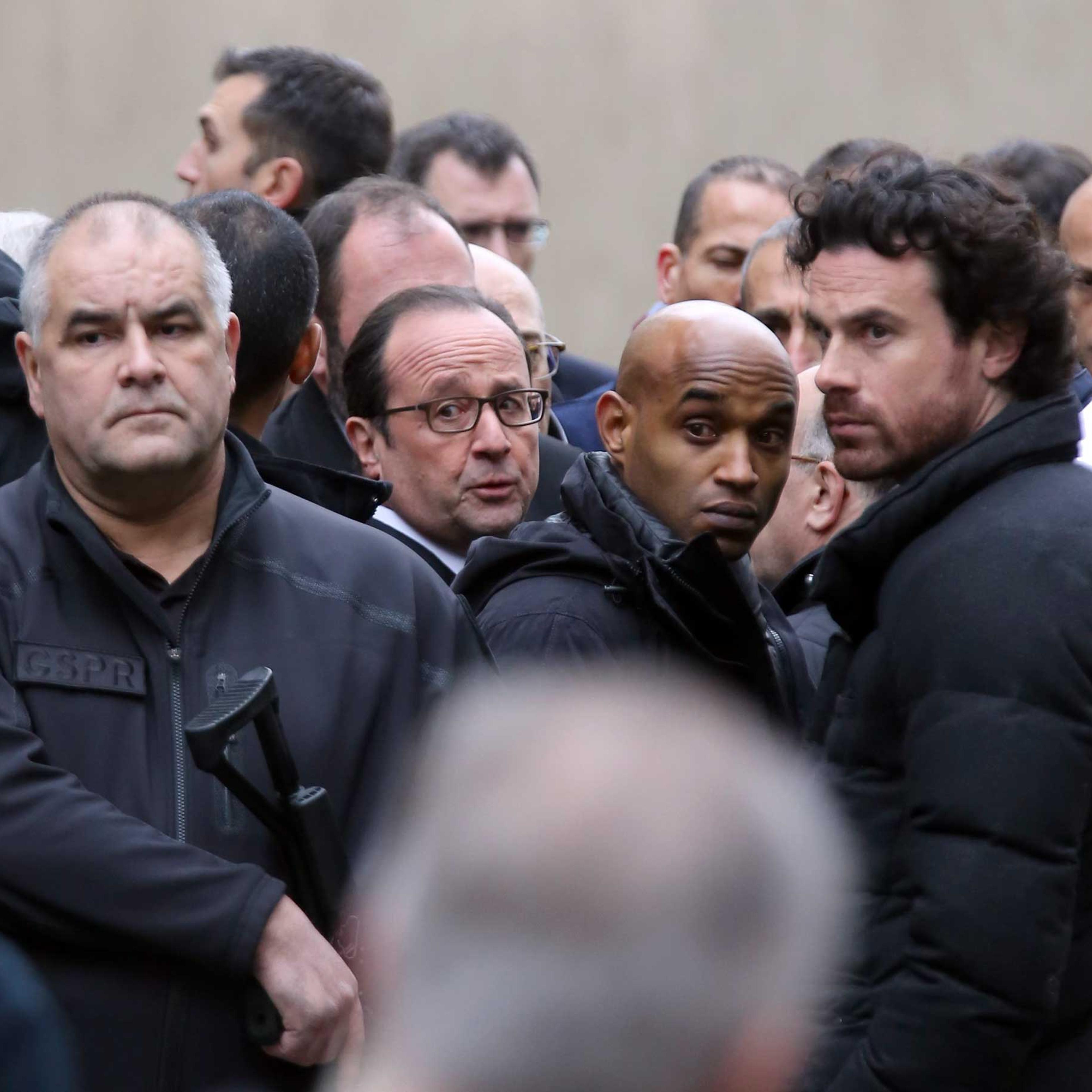 President Francois Hollande, center, flanked with security forces arrives outside the French satirical newspaper Charlie Hebdo's office, in Paris, Jan. 7, 2015.