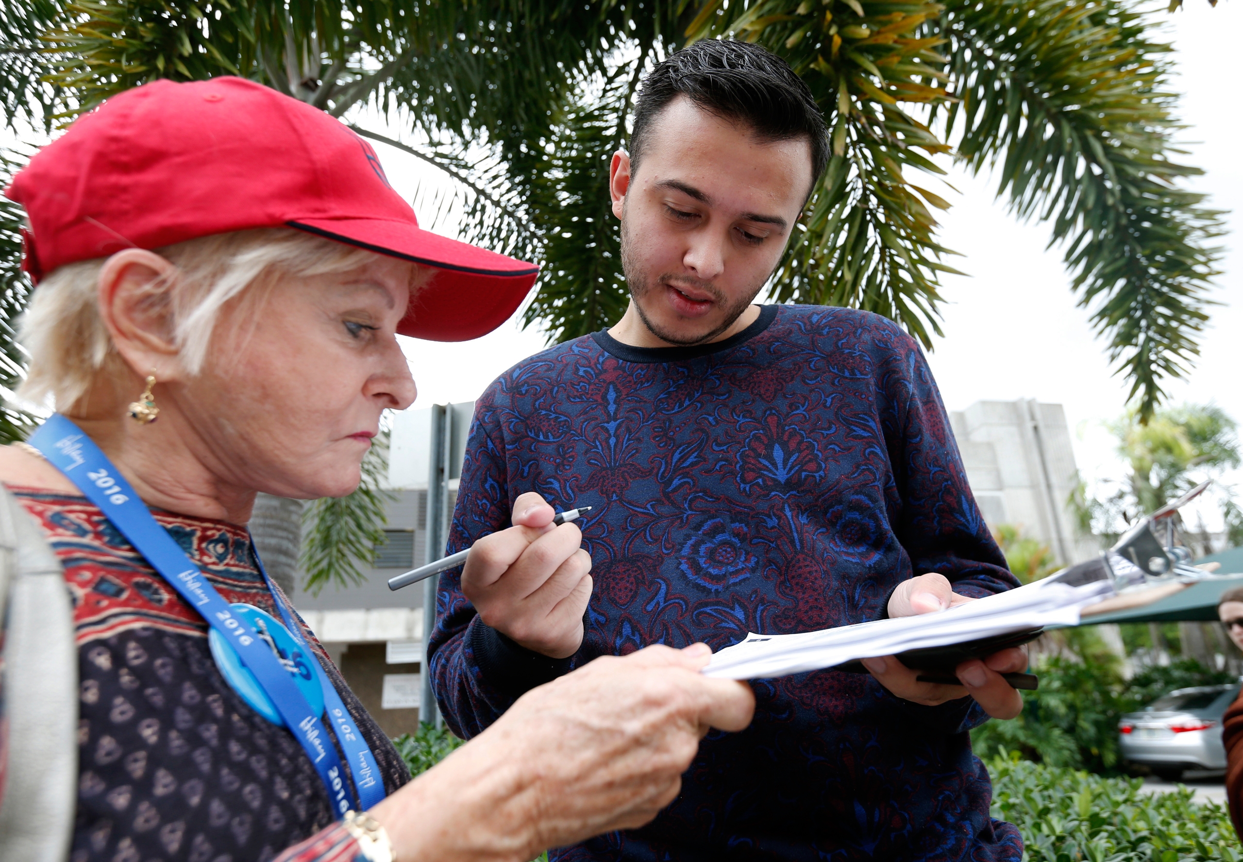 Volunteer Sandi Strickland, left, helps Roman Rodriguez, right, fill out a new voter registration form because of a change of address, as he waits in line to attend a rally for Democratic presidential candidate Hillary Clinton and former vice president A