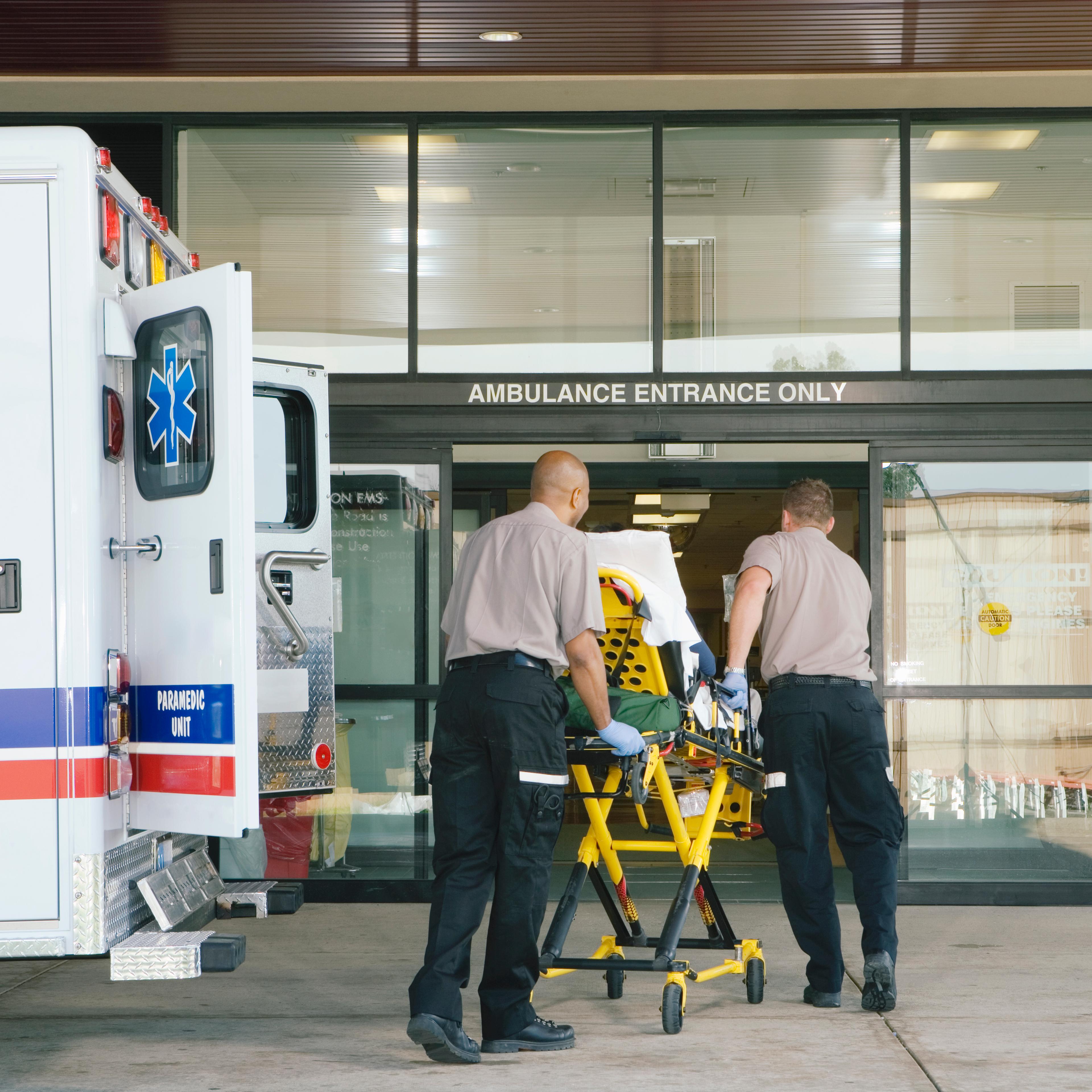 Paramedics taking patient on stretcher from ambulance to hospital