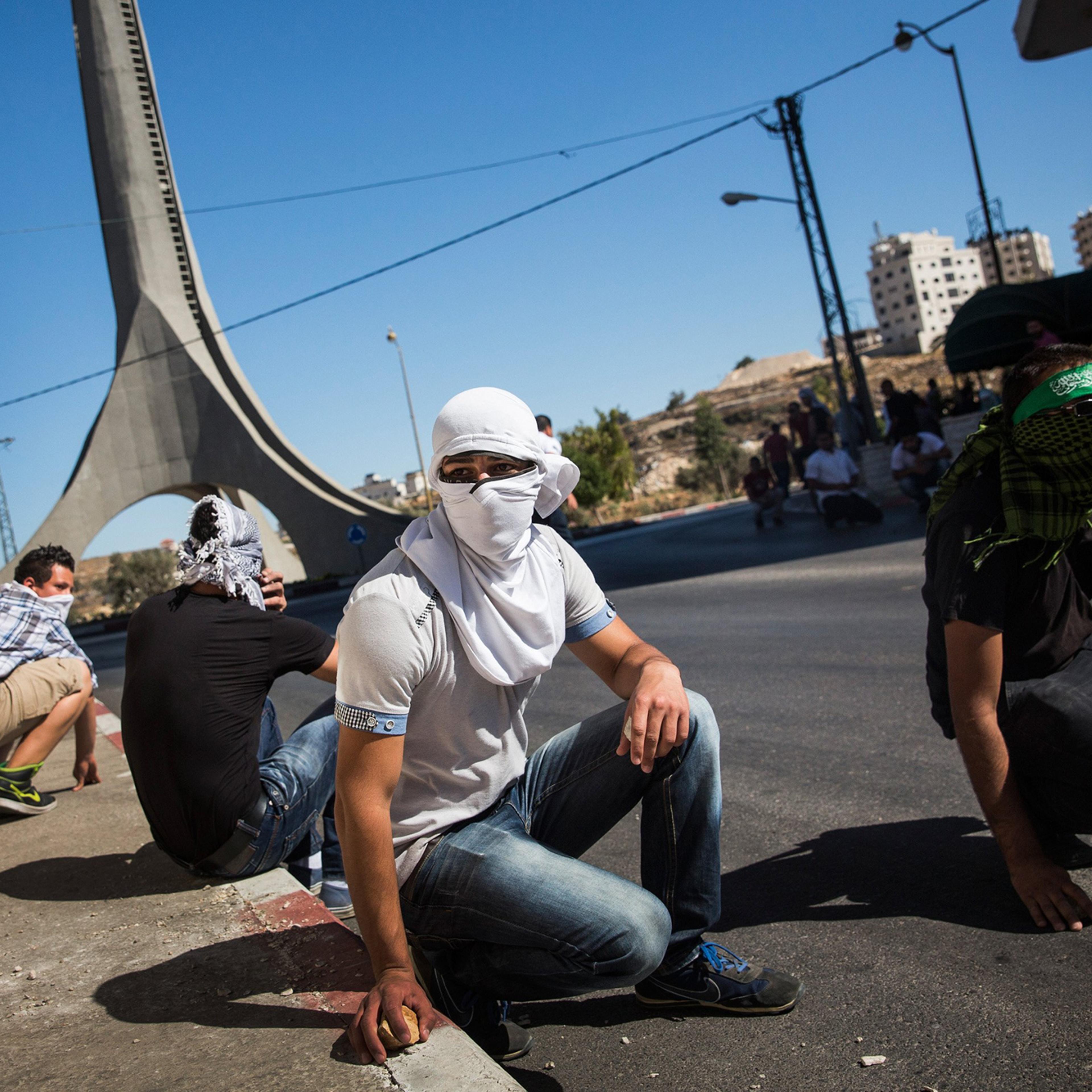 Palestinian supporters of Hamas take shelter while clashing with Israeli security forces on July 25, 2014 near Ramallah, West Bank.