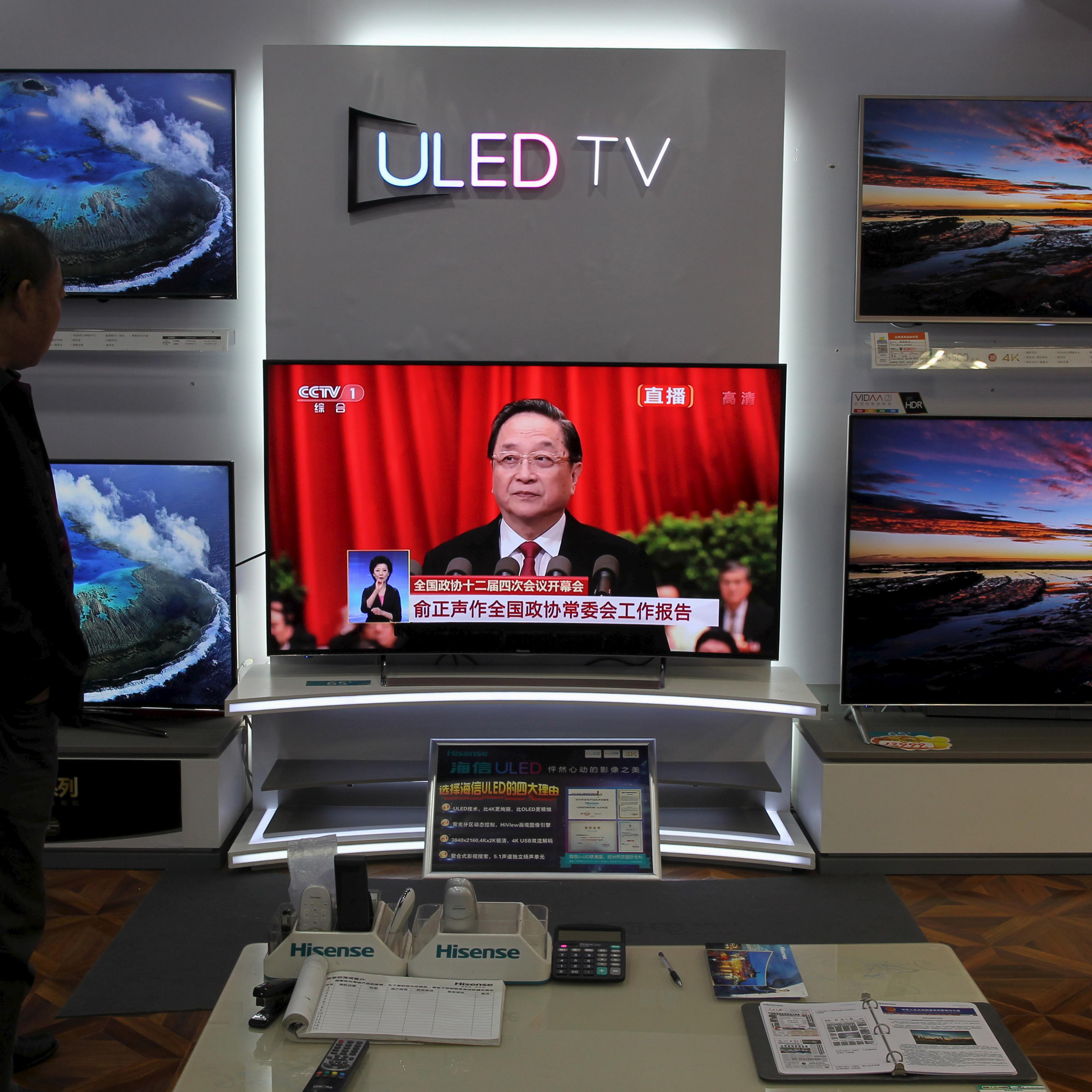 A man watches a TV screen showing live broadcast of Yu giving a speech during the opening session of the CPPCC, at a shopping mall in Kunming