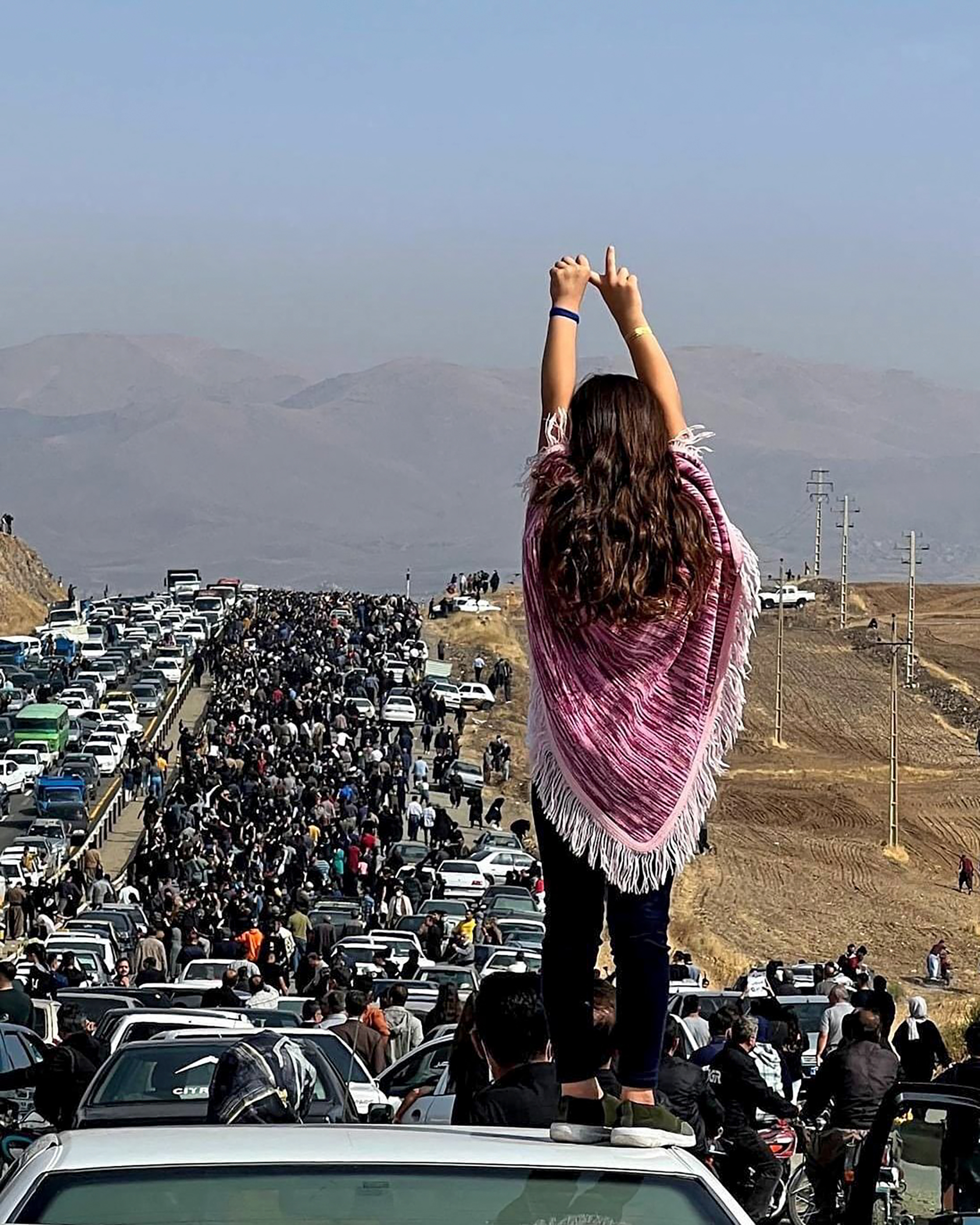 An unveiled woman standing on top of a vehicle as thousands make their way towards Aichi cemetery in Saqez, Mahsa Amini's home town in the western Iranian province of Kurdistan, to mark 40 days since her death, defying heightened security measures as part of a bloody crackdown on women-led protests.